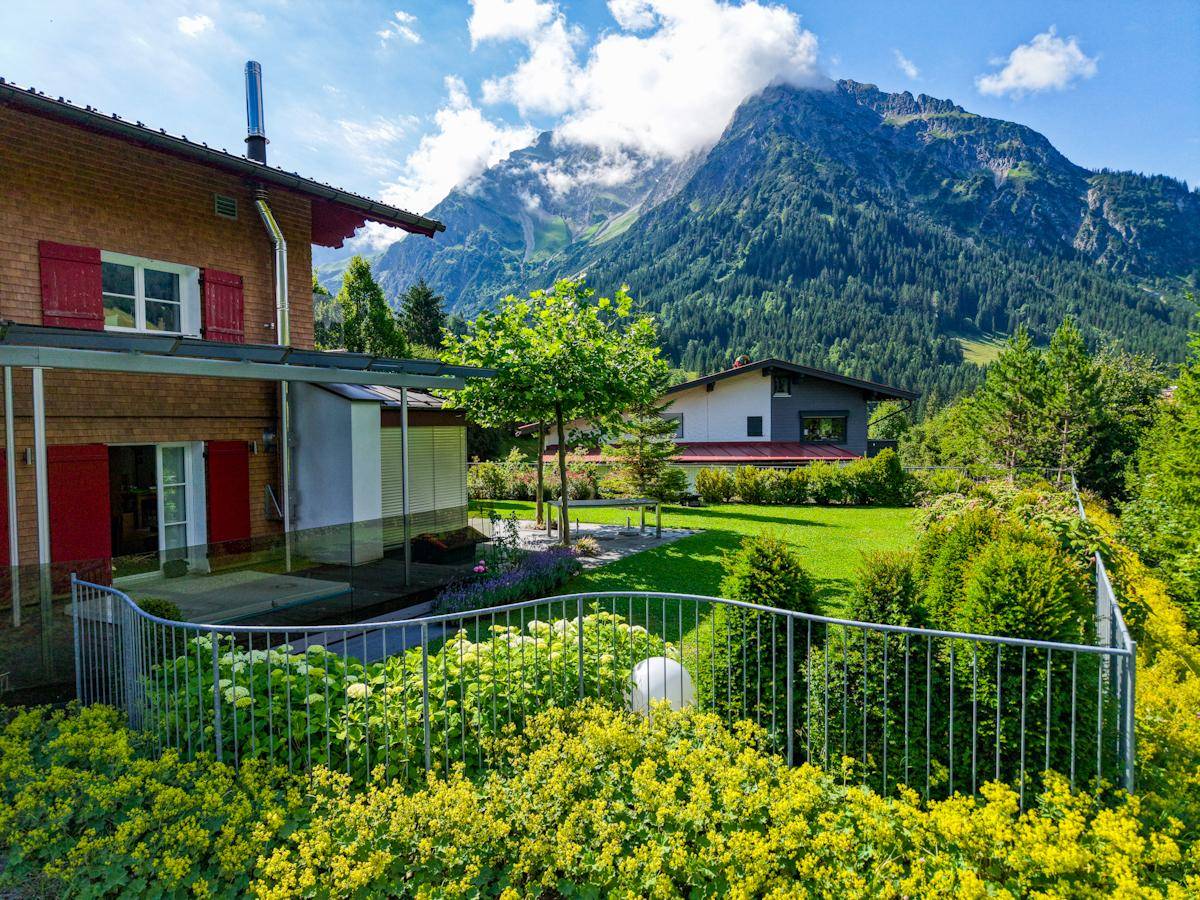Gepflegter Gartenbereich mit Blumenbeeten und Blick auf die umliegenden Berge.