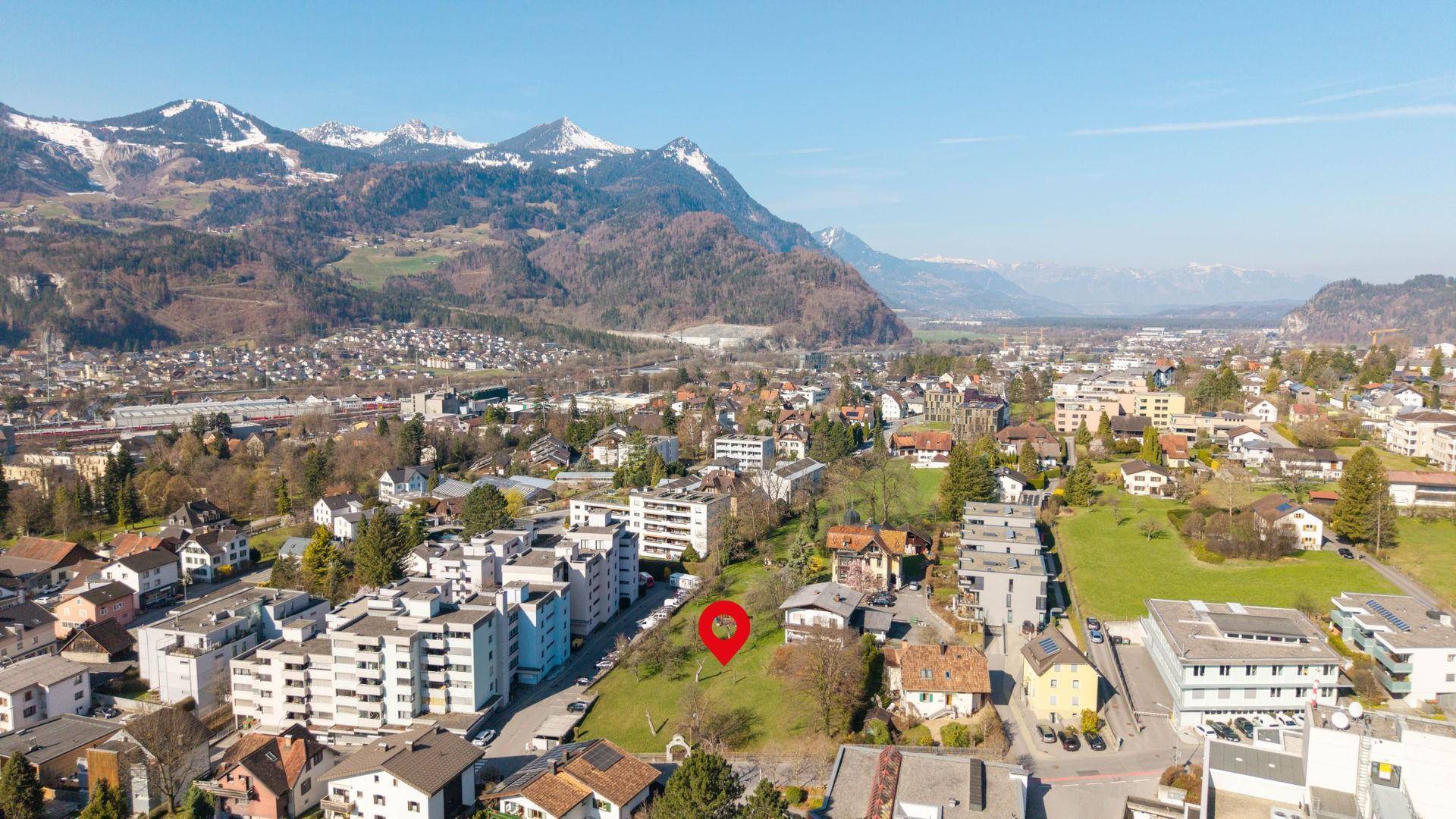 Panoramablick auf eine Stadt mit schneebedeckten Bergen und einem markierten Grundstück.