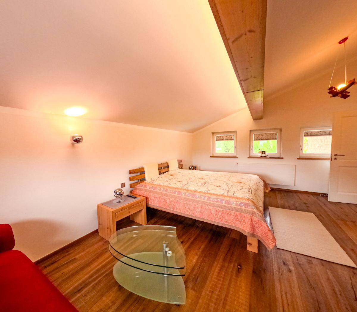 Gemütliches Schlafzimmer mit Holzbalken, Holzboden und Dachschrägen.