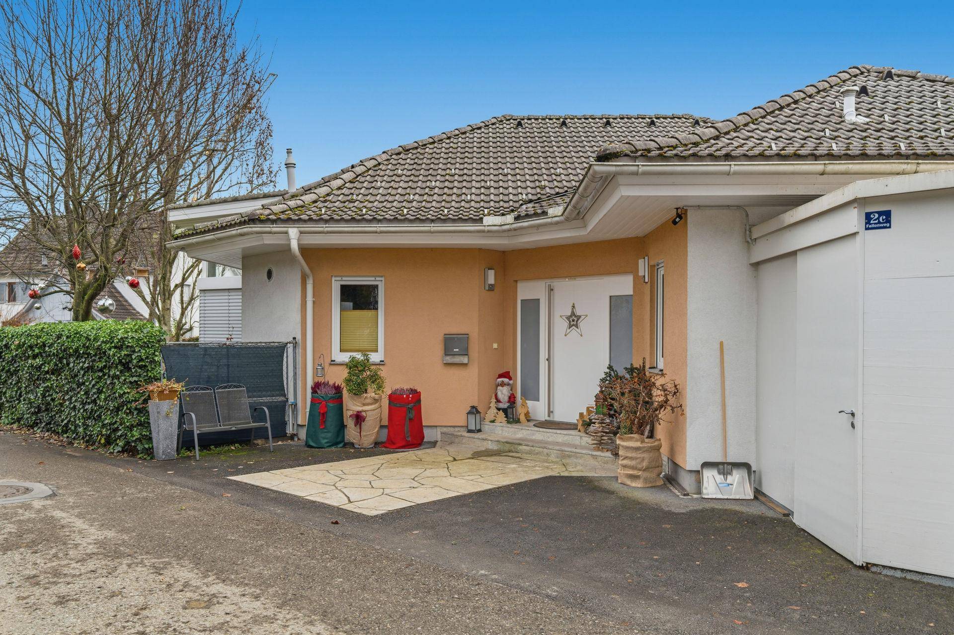 Vorderansicht des Hauses mit Eingangsbereich, gepflastertem Vorplatz und Garage.