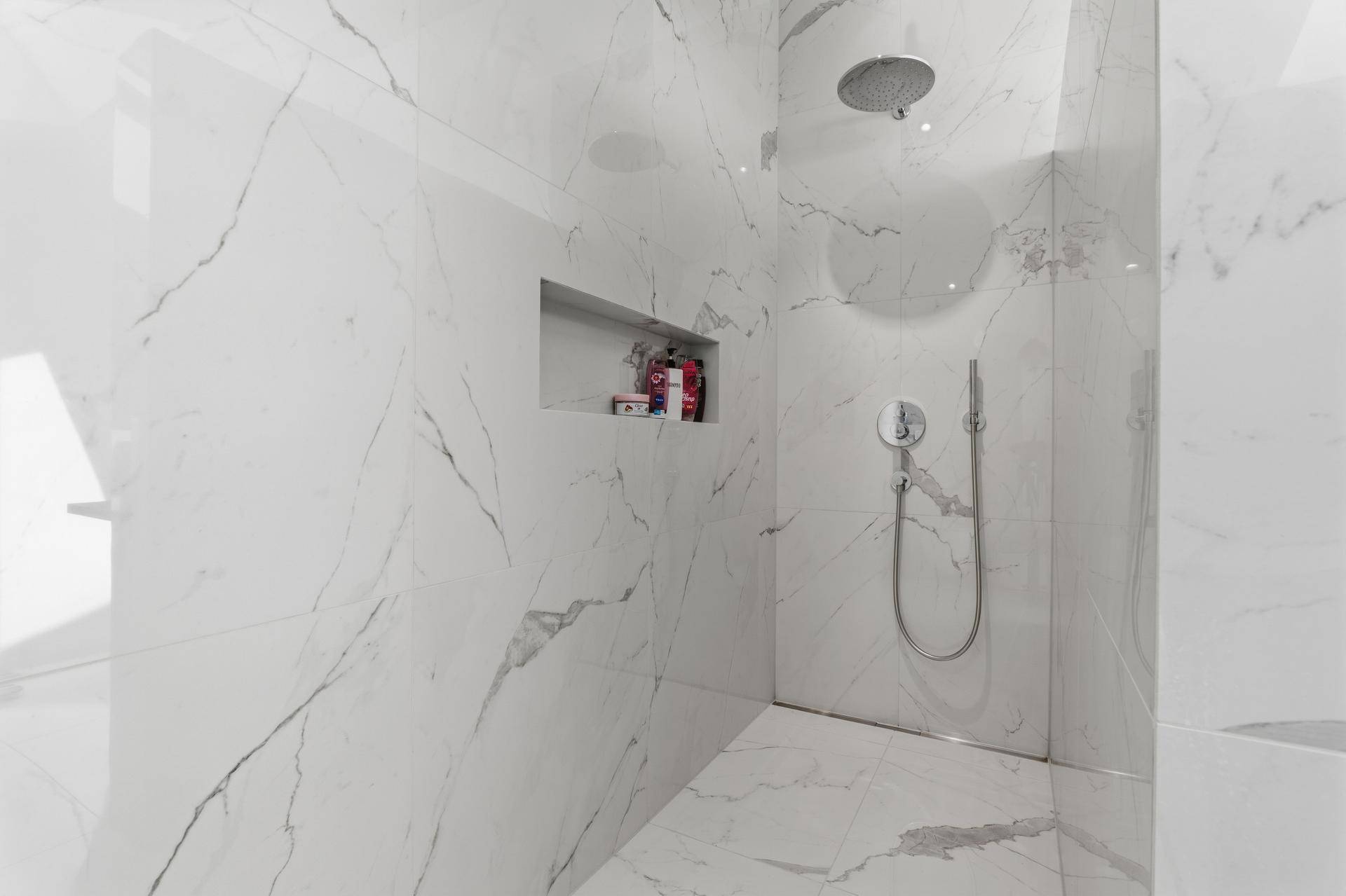 Geräumige begehbare Dusche mit eleganten Marmoroptik-Fliesen und Regenduschkopf.