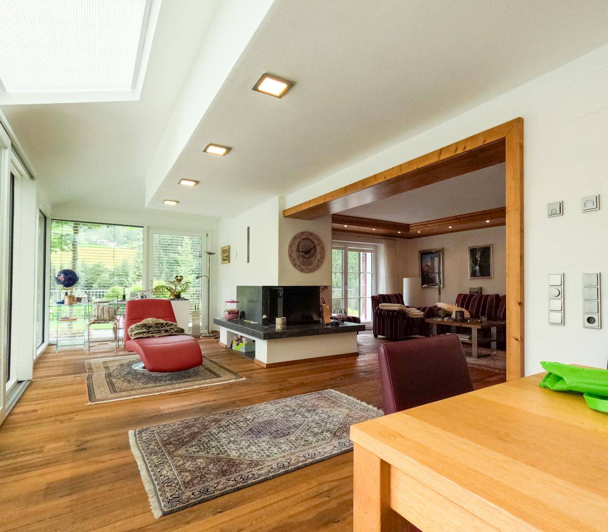 Helles Wohnzimmer mit Kamin, Holzboden und Zugang zum Wintergarten.