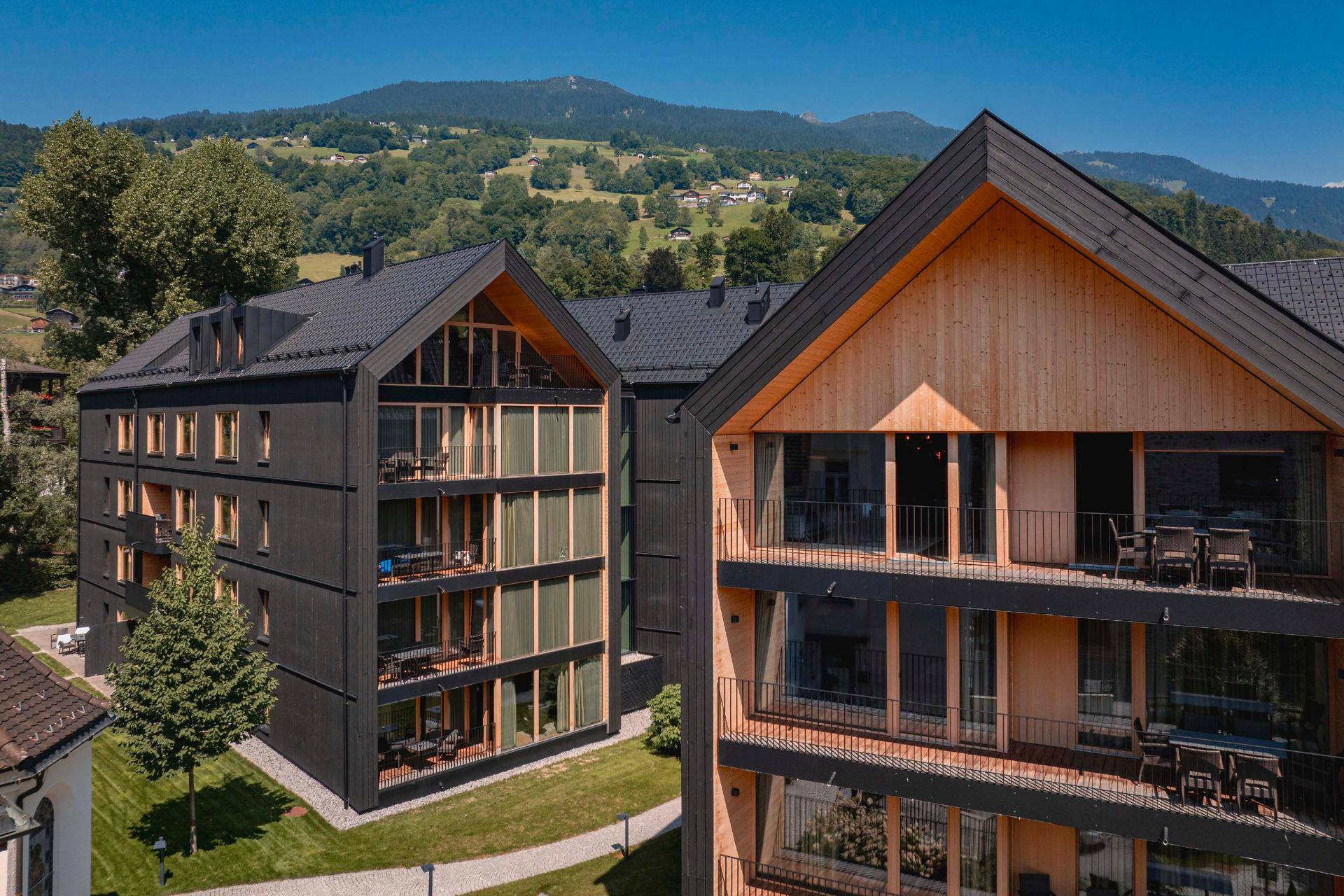 Nahaufnahme der modernen Apartmentgebäude mit großen Glasfronten und Balkonen vor einer Bergkulisse.