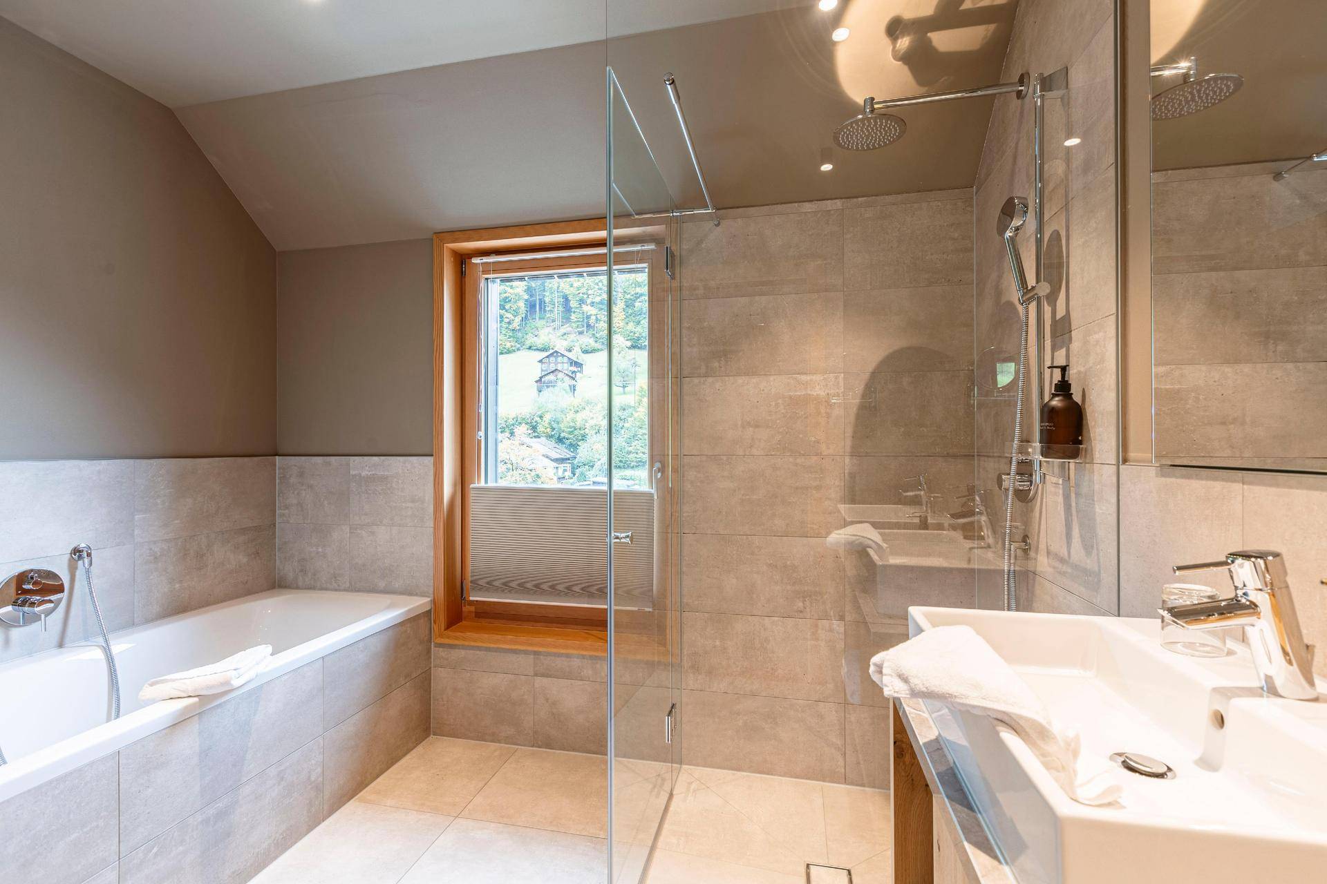 Modernes Badezimmer mit Badewanne, begehbarer Dusche und Fenster mit Bergblick.
