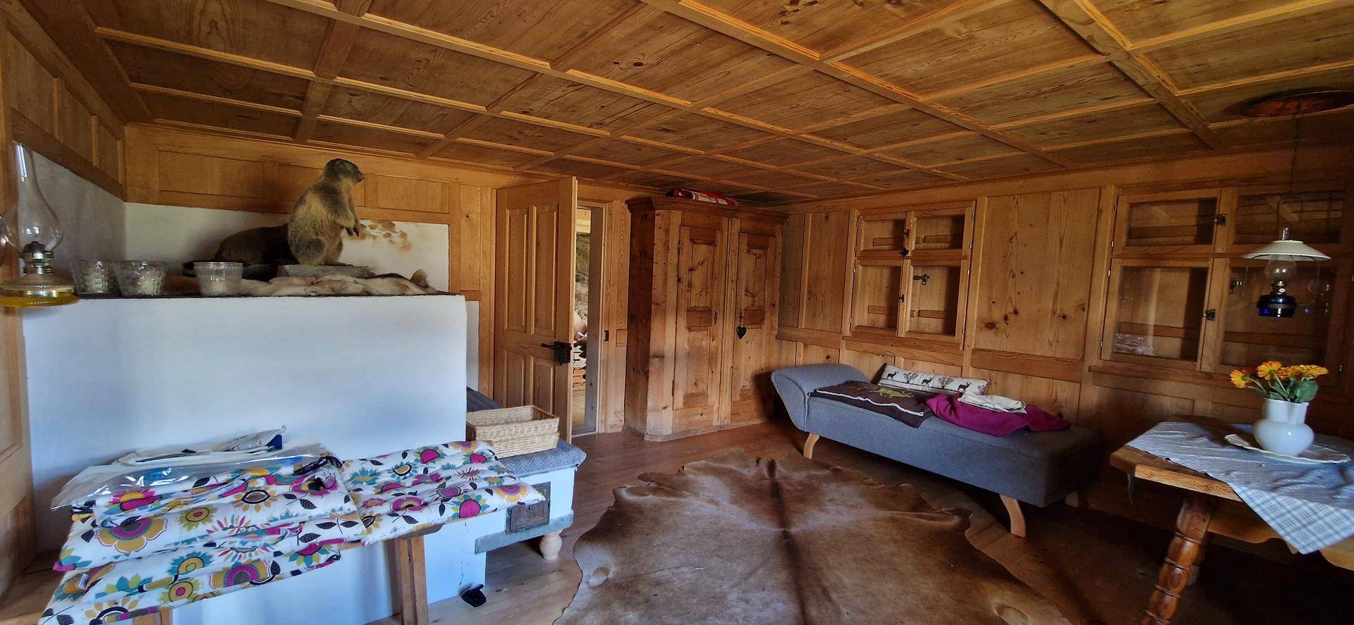 Gemütlicher Wohnbereich mit Holzvertäfelung, Kachelofen und rustikalen Möbeln.