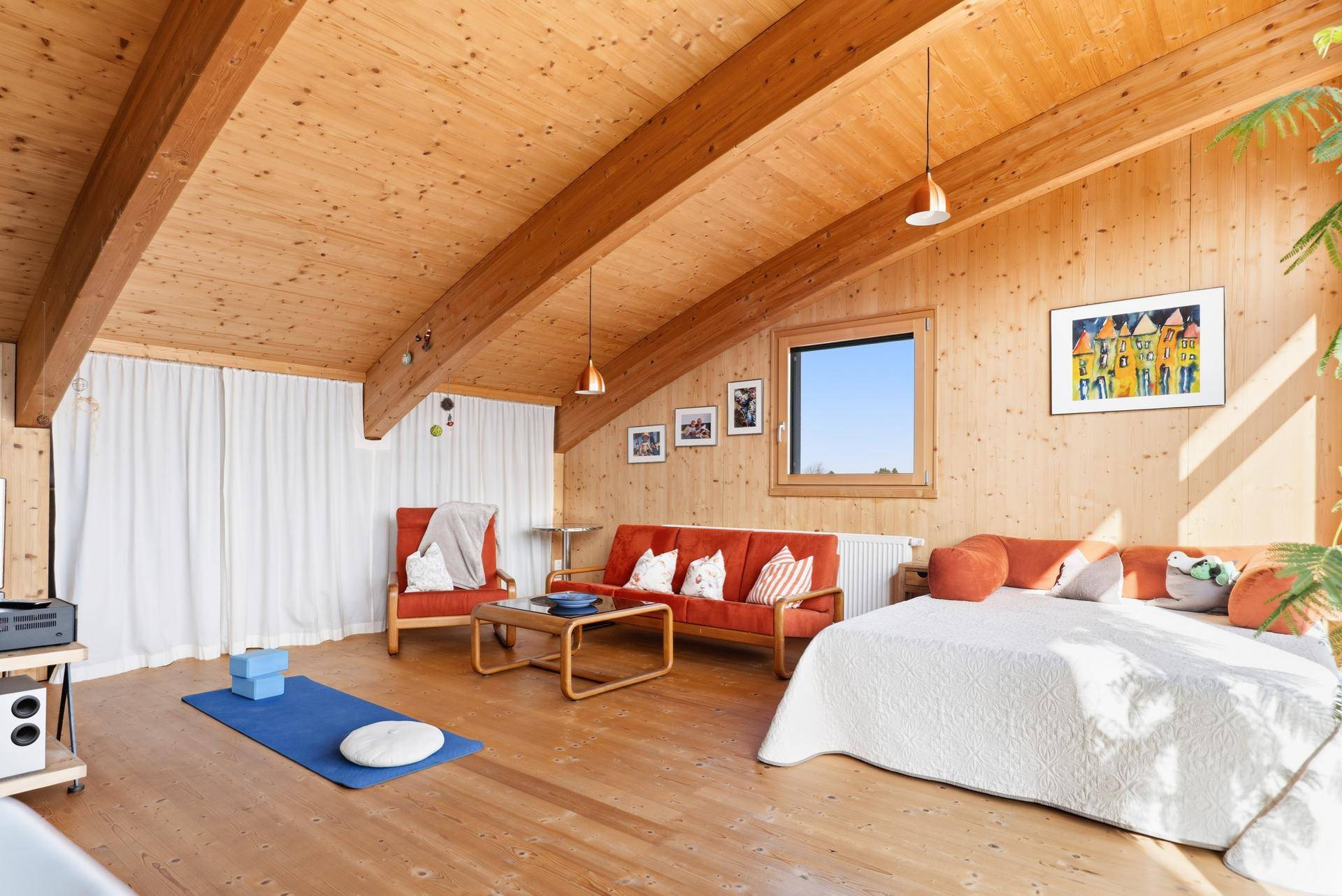 Gemütlicher Wohnbereich mit Holzwänden, Holzbalken und einem bequemen Bett, ideal zum Entspannen.
