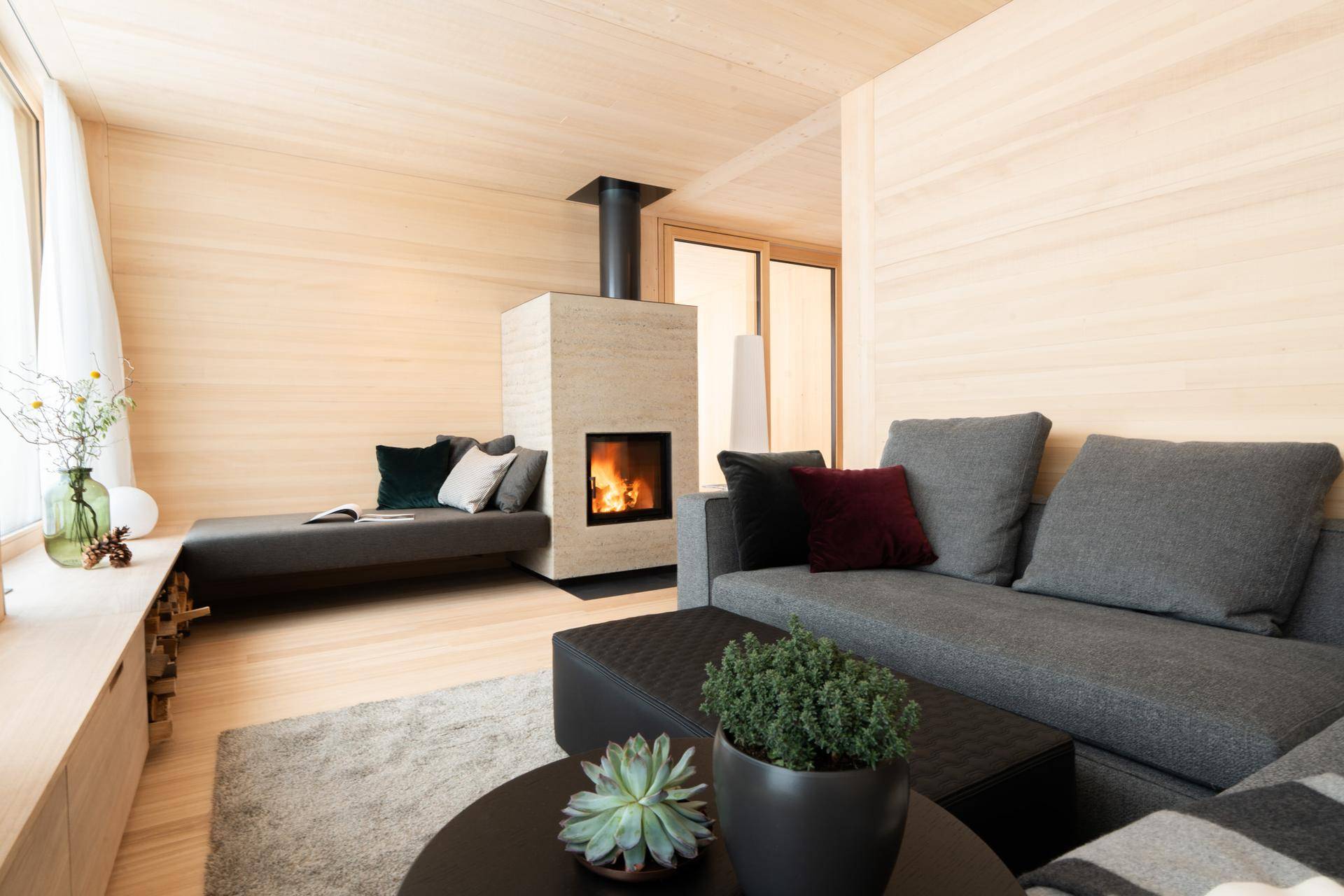 Gemütliches Wohnzimmer mit modernem Kamin, bequemen Sofas und heller Holzverkleidung.