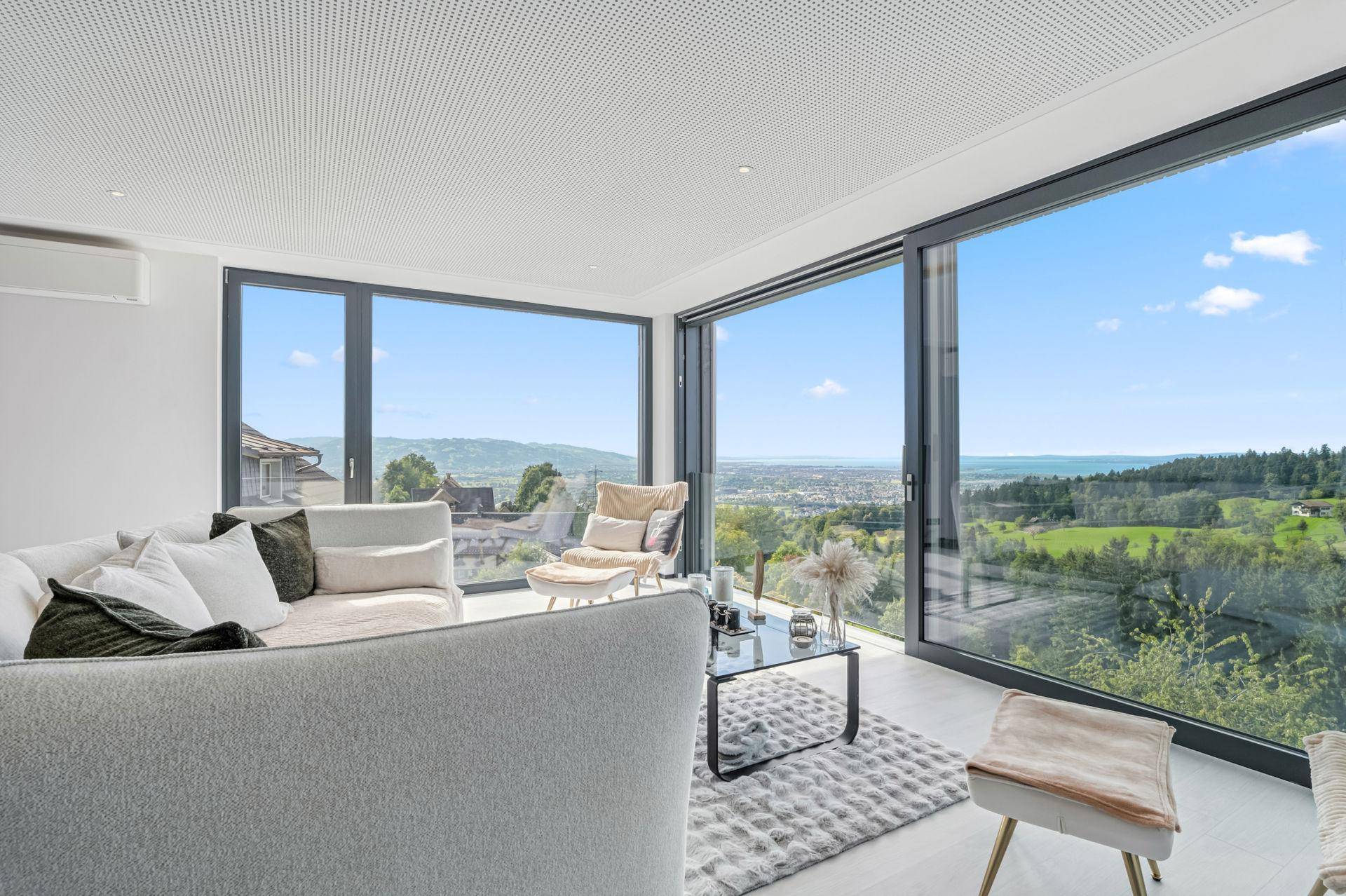 Helles, modernes Wohnzimmer mit raumhohen Fenstern und weitem Blick über die Landschaft.