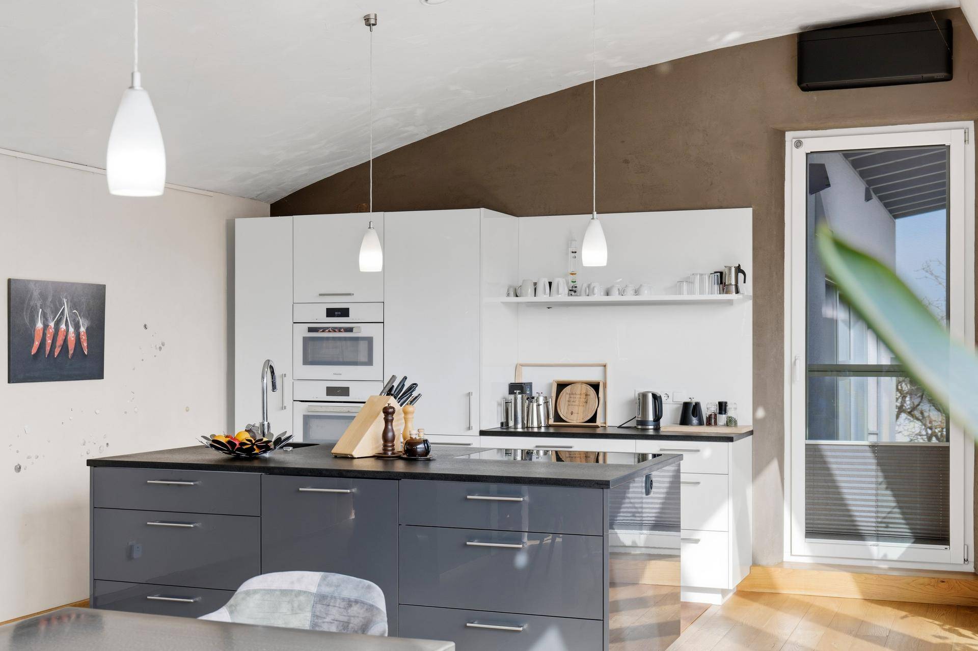 Moderne Küche mit grauer Kochinsel und weißen Wandschränken, gut beleuchtet durch ein Fenster.