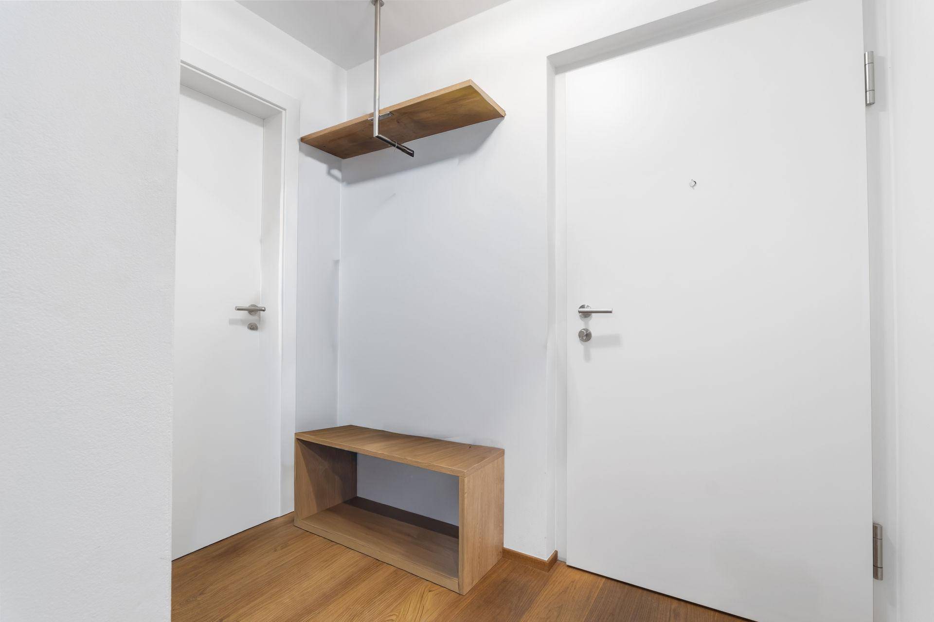 Heller Eingangsbereich mit Holzboden, einer schlichten Garderobenbank und praktischer Ablagefläche.