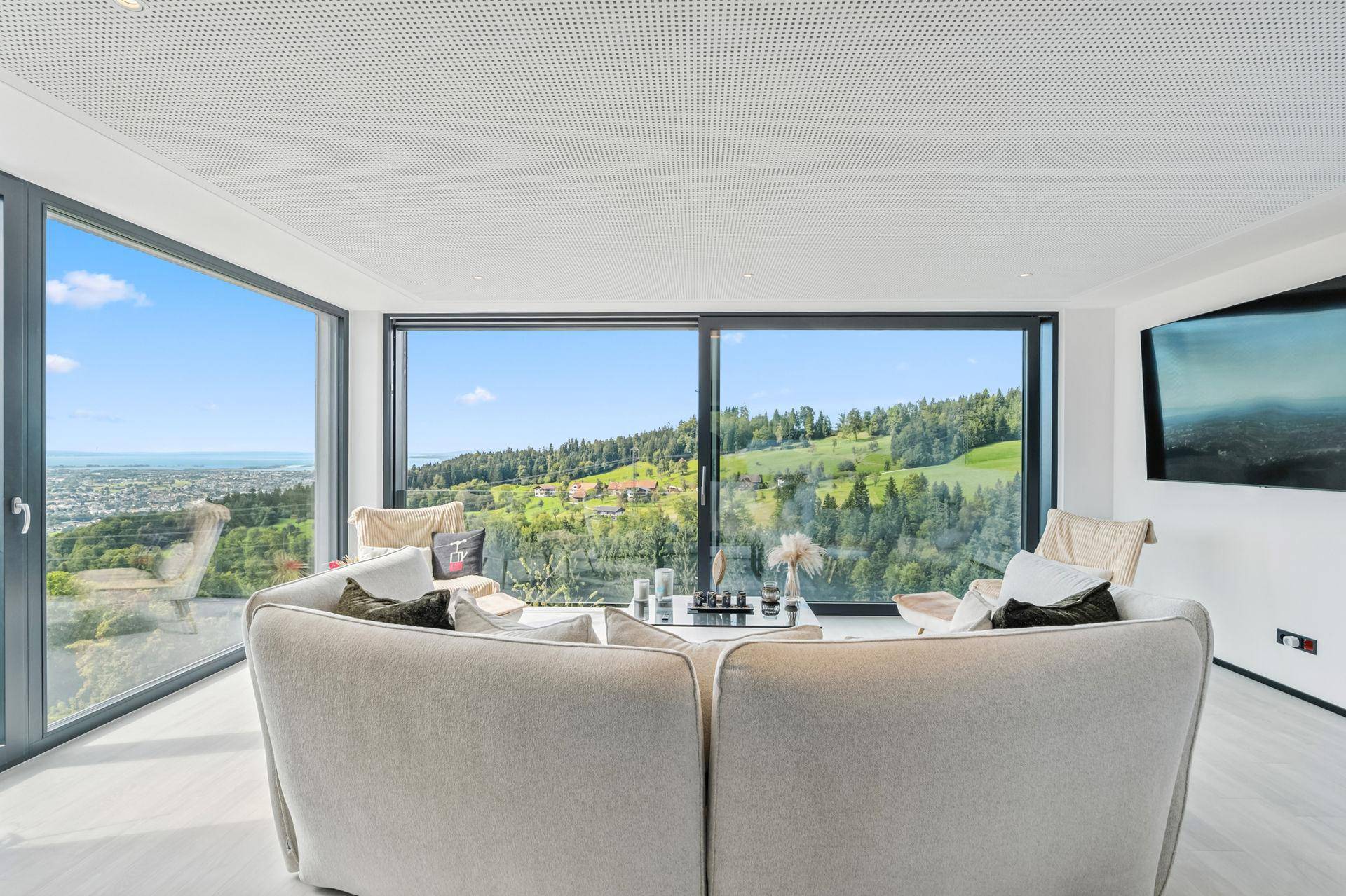 Geräumiges Wohnzimmer mit bequemen Sofas und beeindruckendem Panoramablick durch große Fenster.