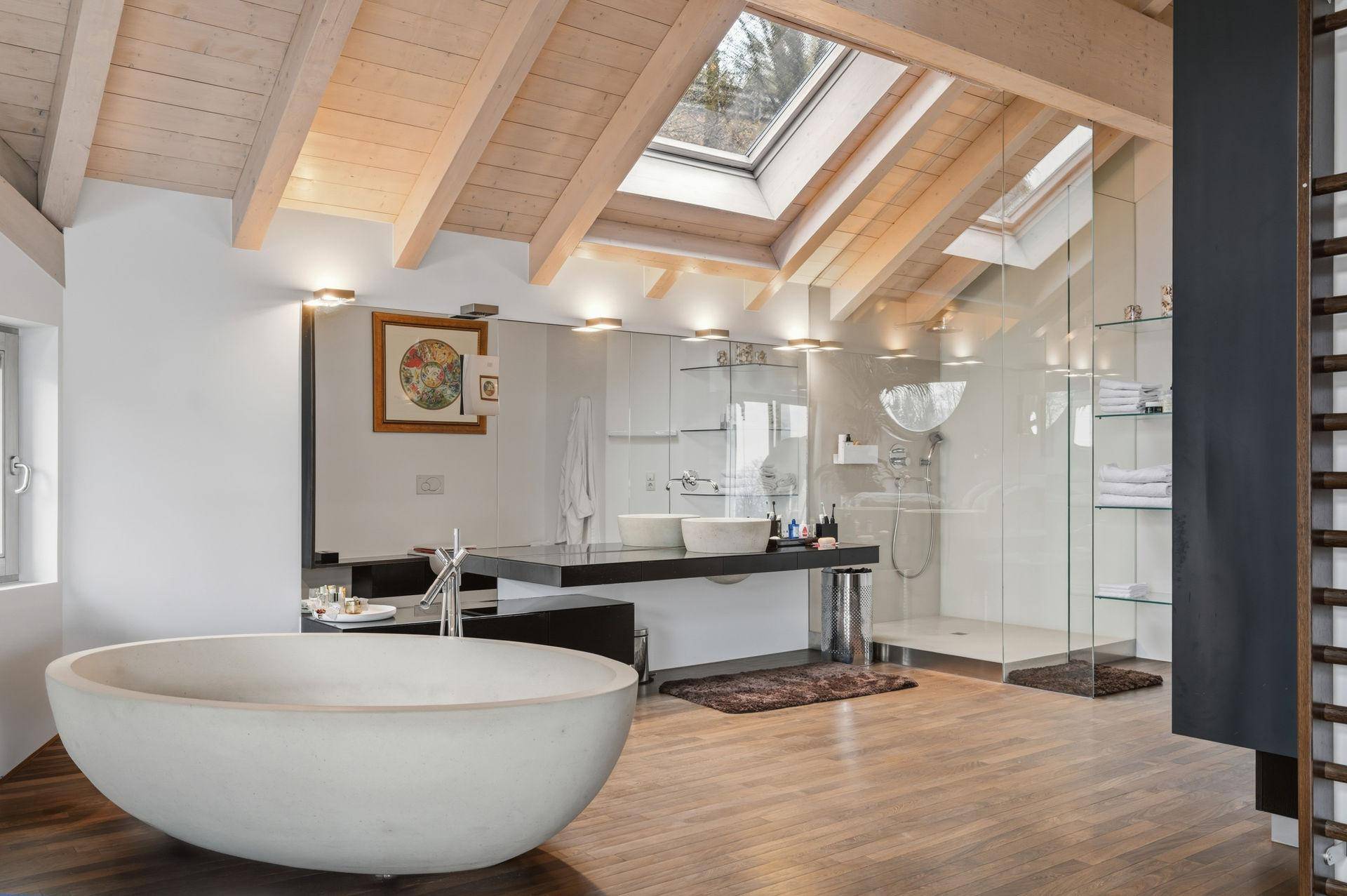 Modernes Badezimmer mit freistehender Badewanne, Doppelwaschbecken und Dachfenstern unter Holzbalken.