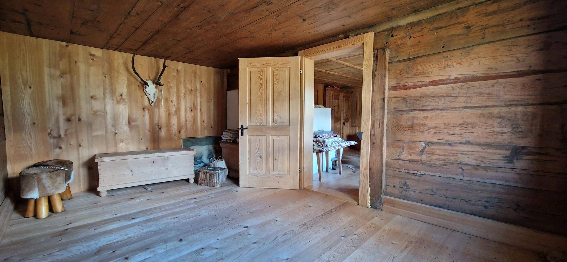 Rustikaler Flur mit Holzwänden, Holzboden und traditioneller Hirschgeweih-Dekoration.