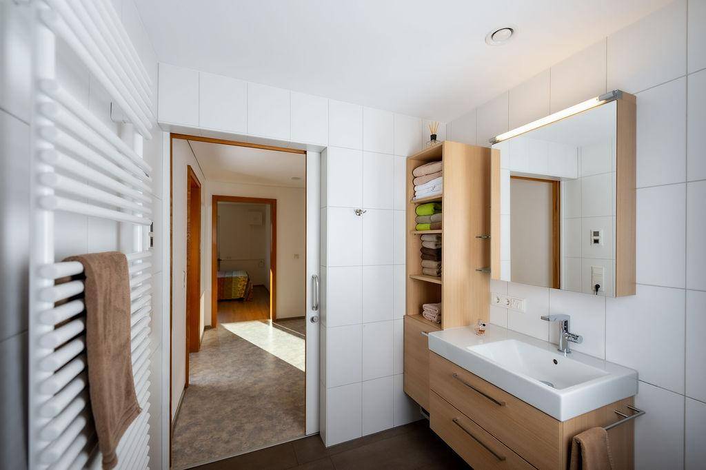 Helles Badezimmer mit modernem Waschtisch, Spiegelschrank und beheiztem Handtuchhalter.