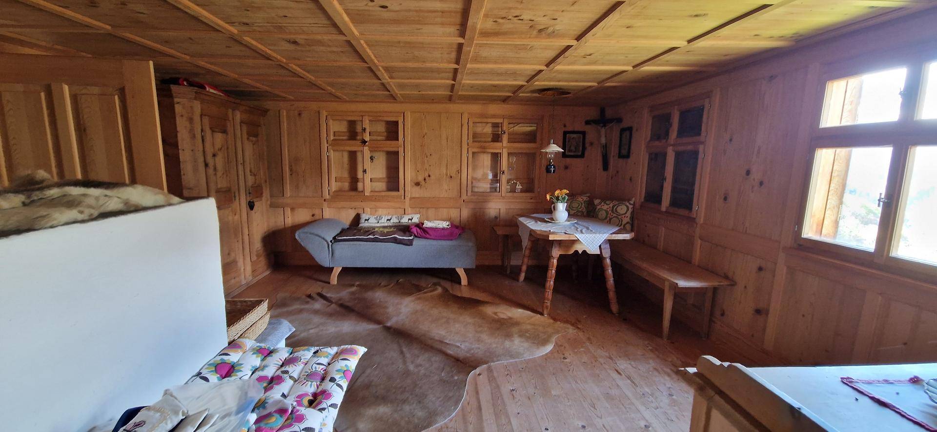 Gemütliches Wohnzimmer mit rustikalen Holzvertäfelungen, Holzboden und traditionellen Möbeln.