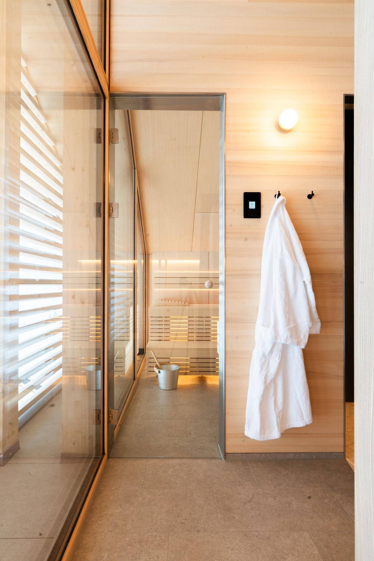 Eingang zu einer modernen Sauna mit Holzwänden und Glasfront, bereit für Entspannung.