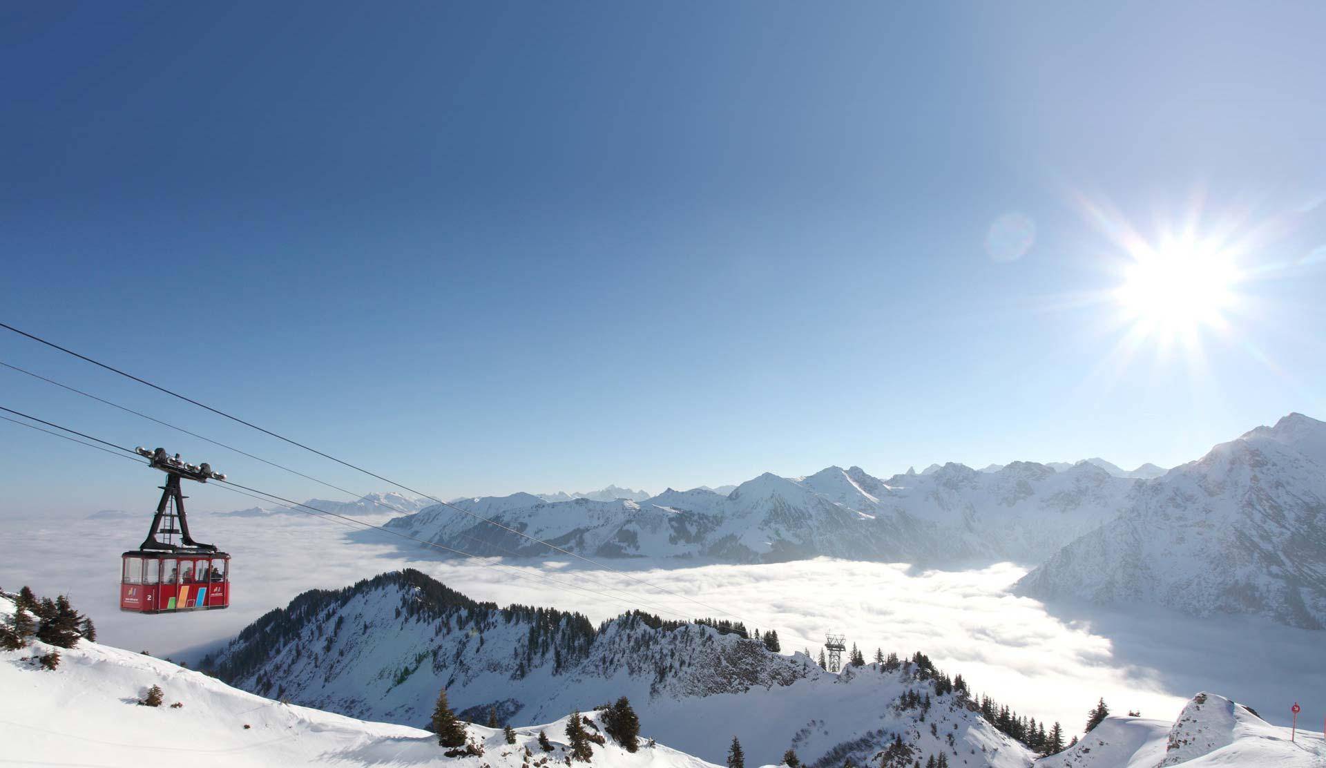 Seilbahn fährt über eine verschneite Berglandschaft unter strahlend blauem Himmel.