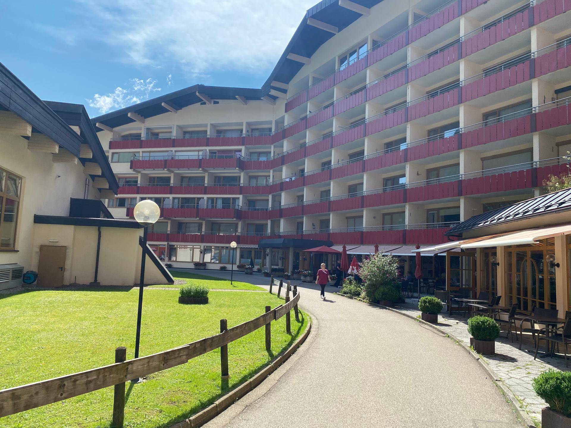 Außenansicht des Gebäudes vom Innenhof mit Rasenfläche und Außengastronomie.