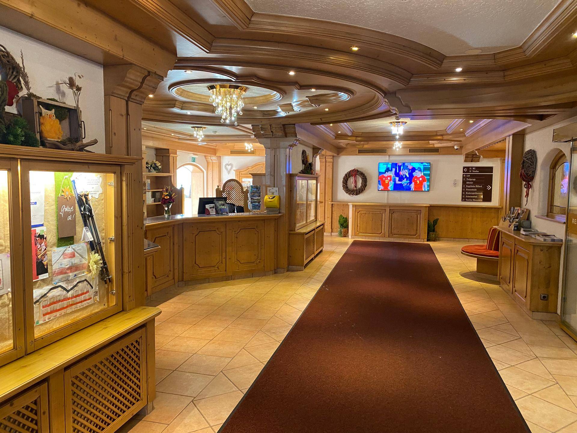 Traditionelle Hotellobby mit Holzvertäfelung, Rezeption und gemütlicher Atmosphäre.
