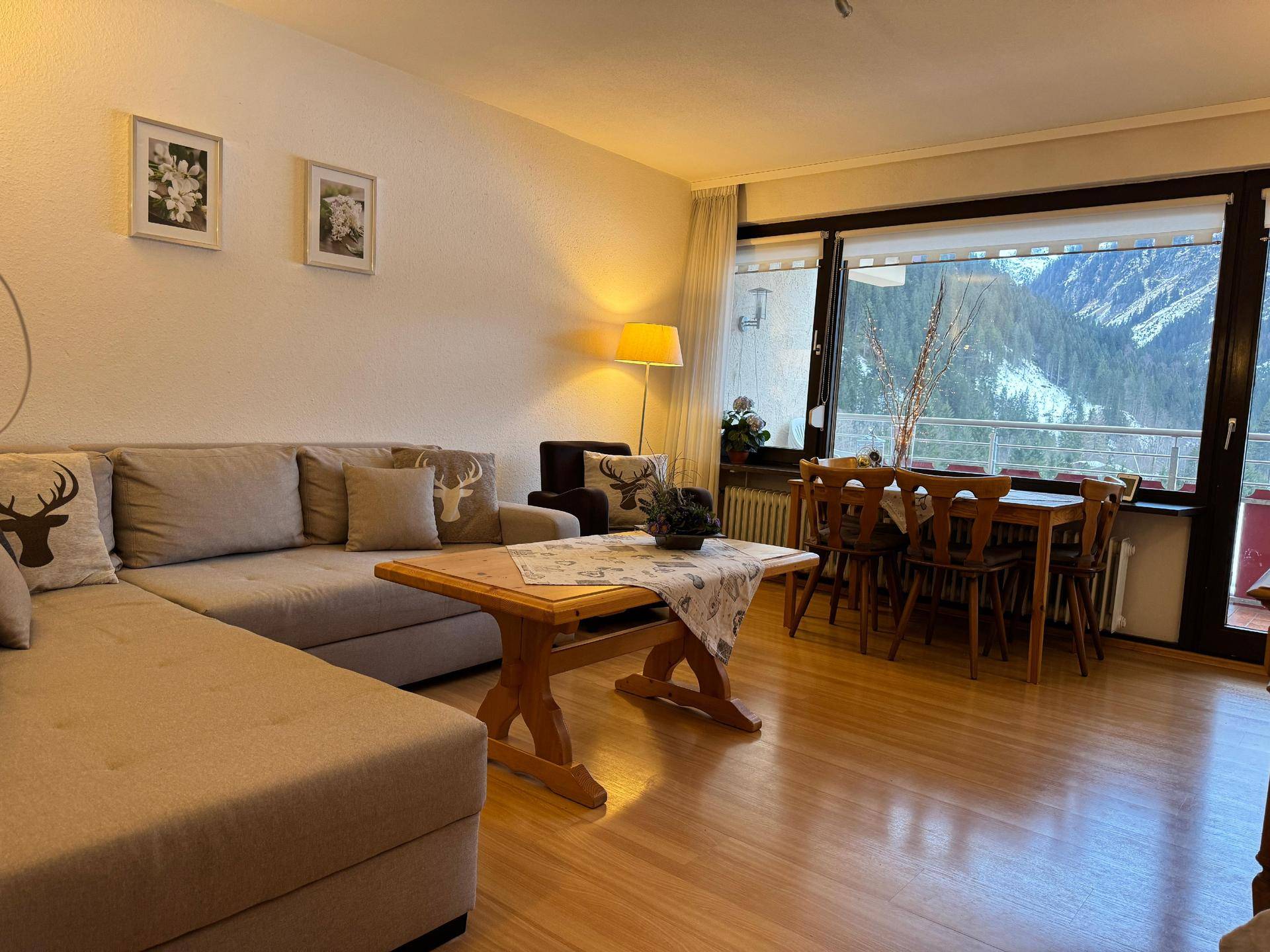 Geräumiger Wohn-Essbereich mit großem Sofa, Holztisch und Panoramablick auf die Berge.
