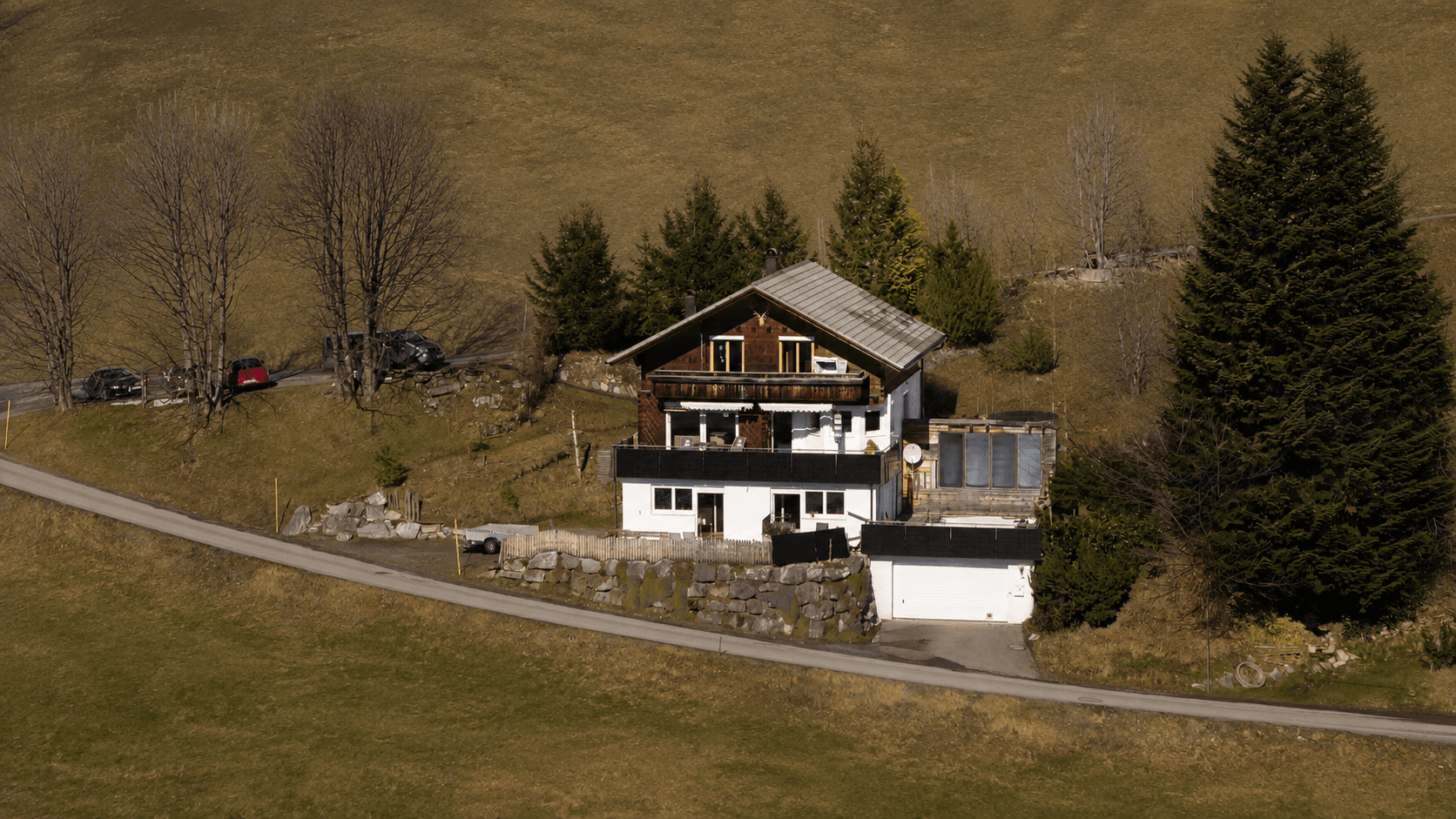 Traditionelles Haus in ländlicher Umgebung mit umliegenden Wiesen und Bäumen.