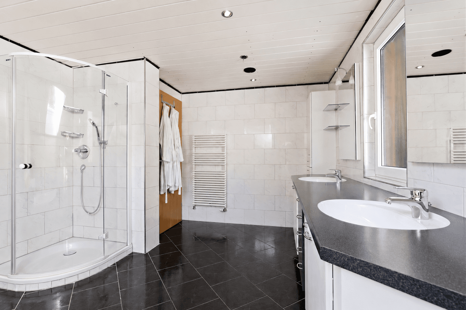Modernes Badezimmer mit Doppelwaschbecken, Duschkabine und beheiztem Handtuchhalter.