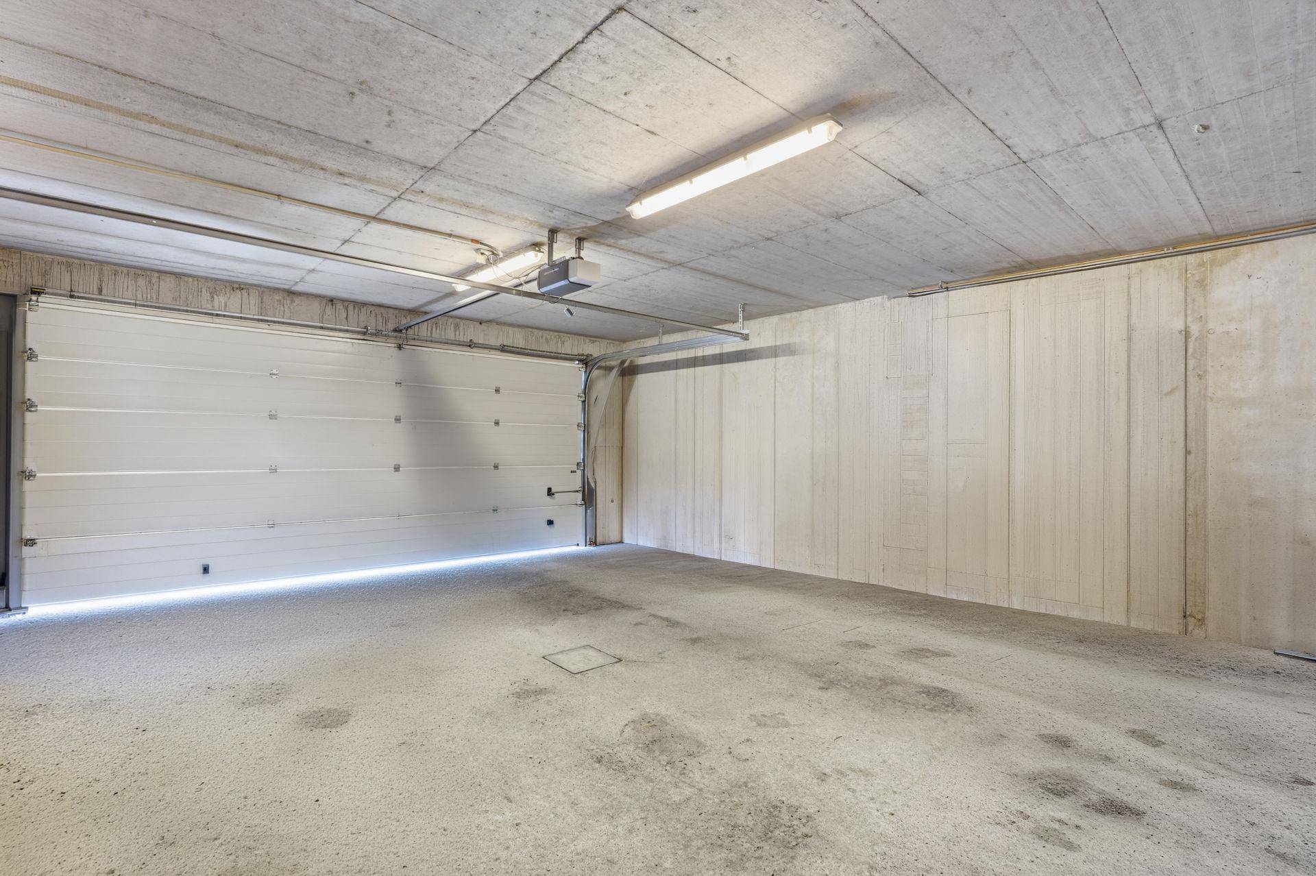 Geräumige Garage mit Betonboden und automatischem Garagentor, bietet Platz für Fahrzeuge.