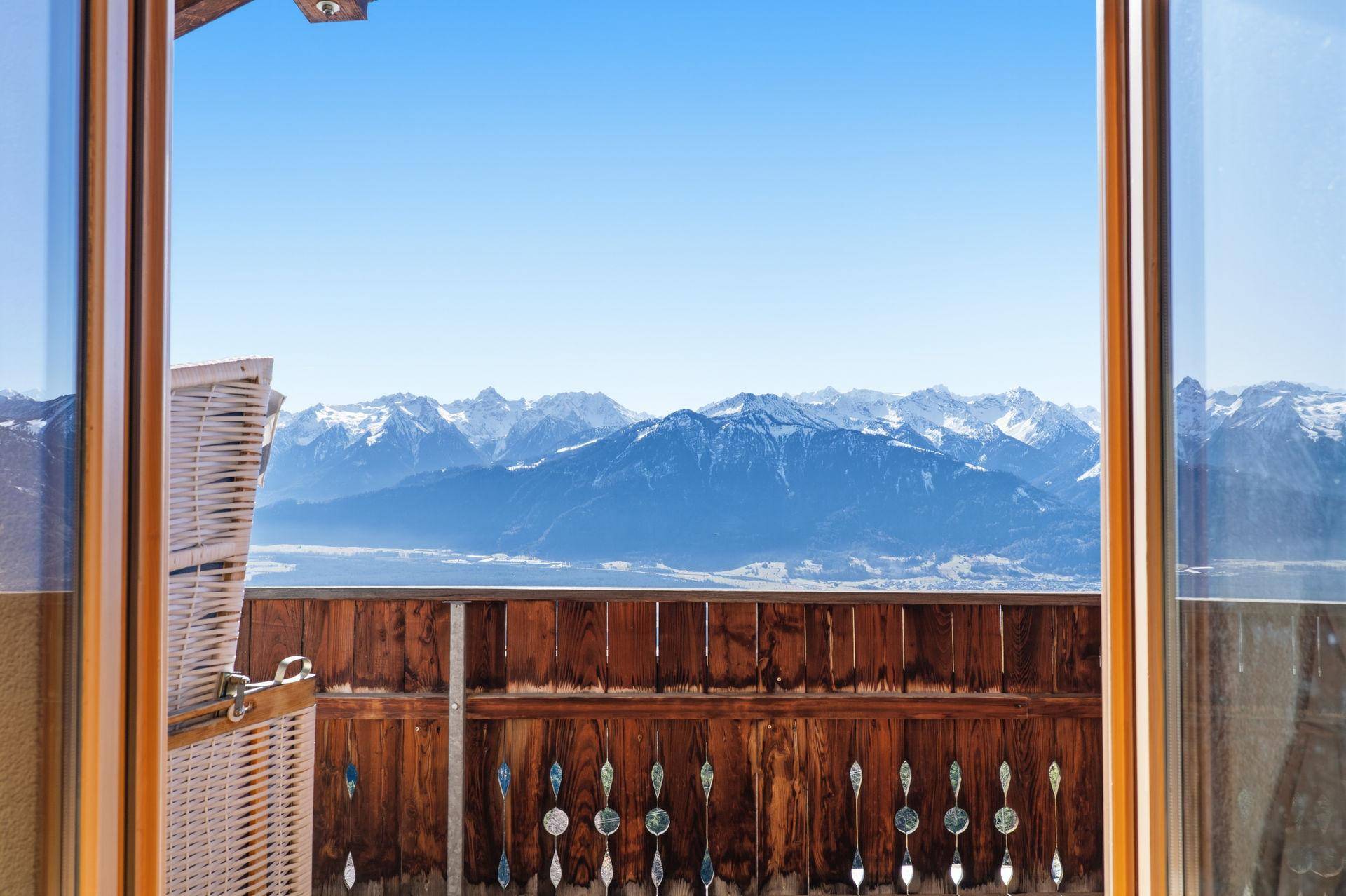 Atemberaubender Bergblick durch eine Balkontür, umrahmt von traditionellem Holzgeländer.