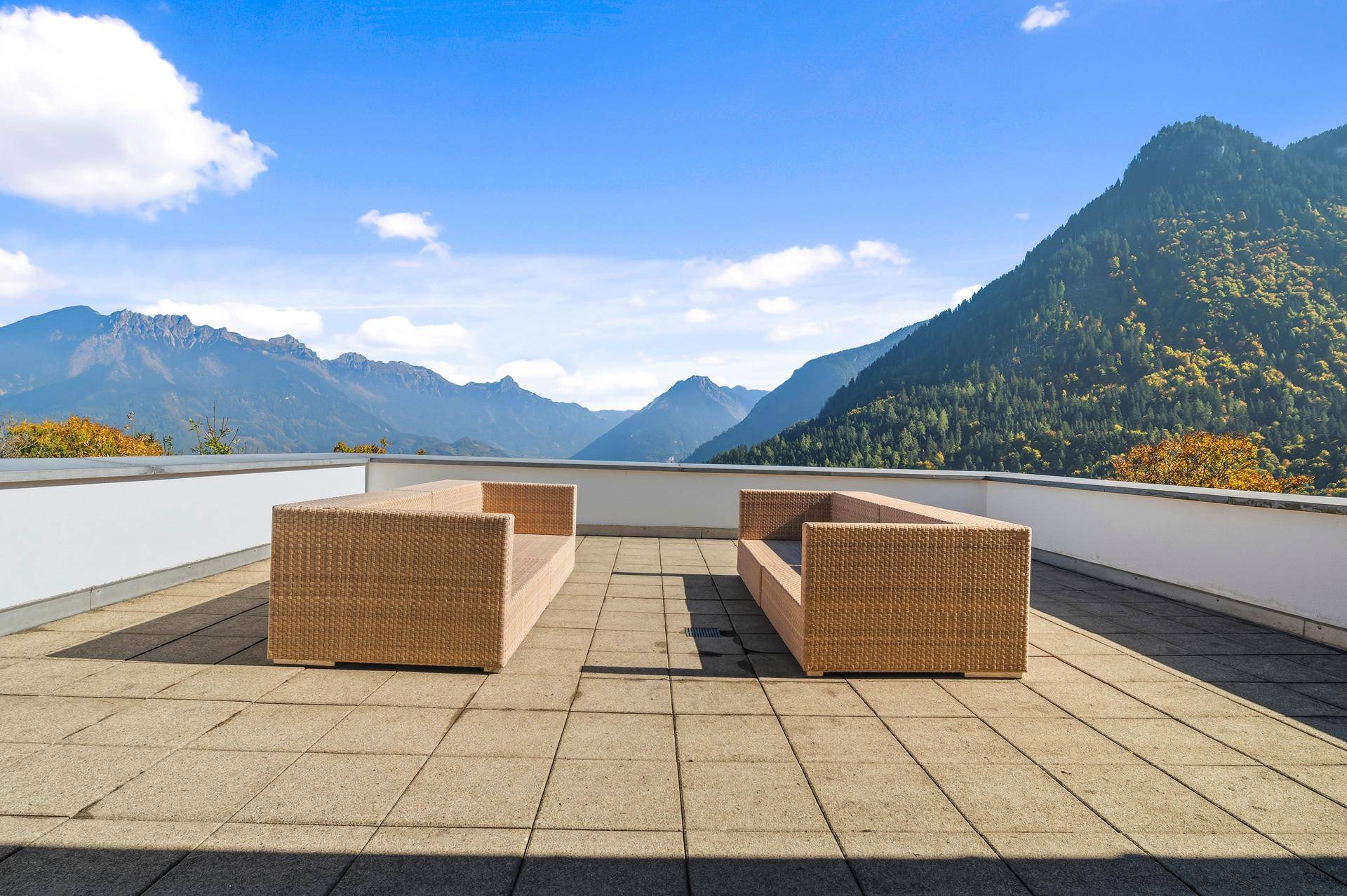Geräumige Terrasse mit bequemen Lounge-Möbeln und weitem Blick auf die Bergwelt.