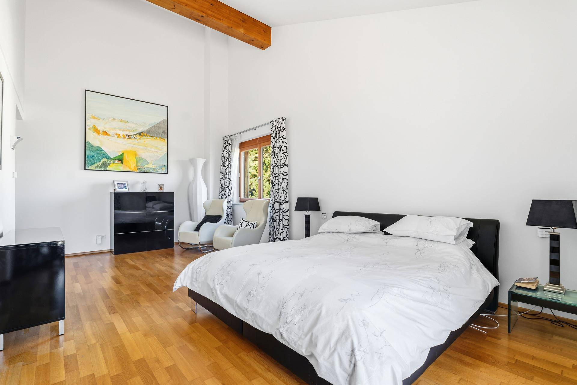Helles Schlafzimmer mit hohen Decken, Holzboden und moderner Einrichtung.