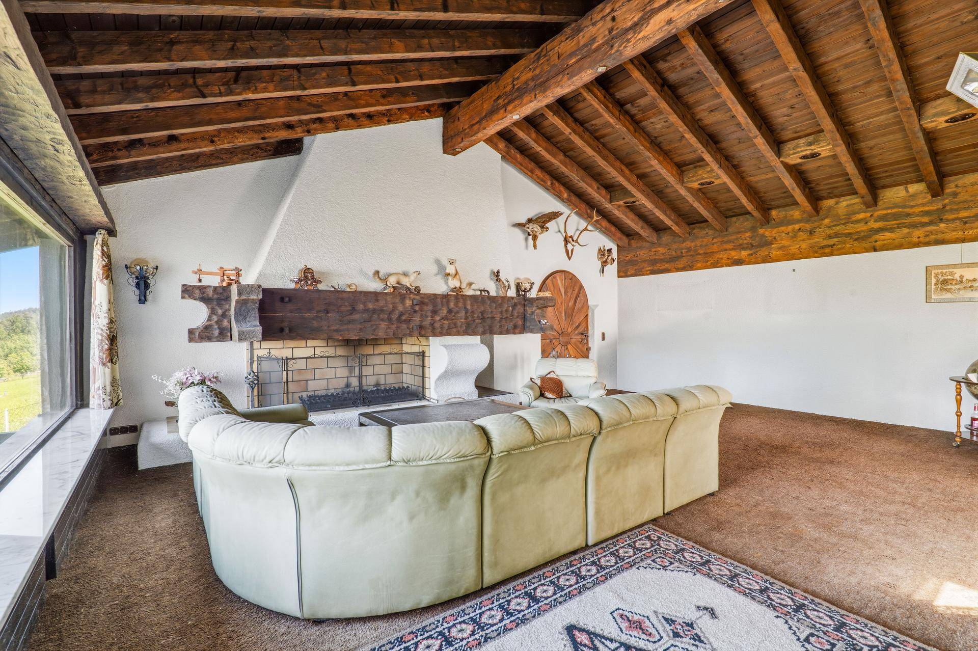 Rustikales Wohnzimmer mit imposantem Kamin, freiliegenden Holzbalken und traditioneller Dekoration.