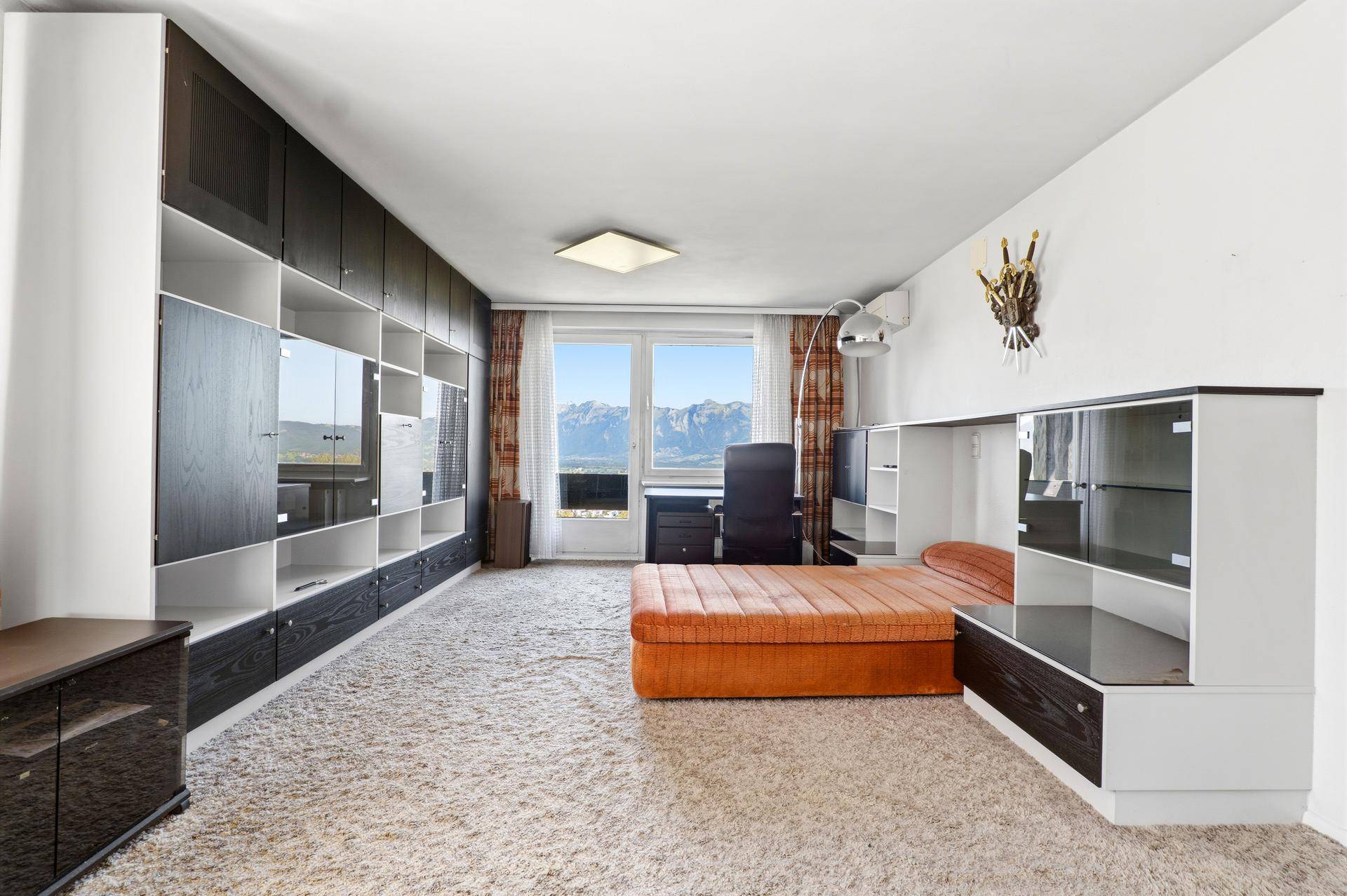 Schlafzimmer mit integrierten Schränken und einem Fenster, das einen weiten Bergblick ermöglicht.
