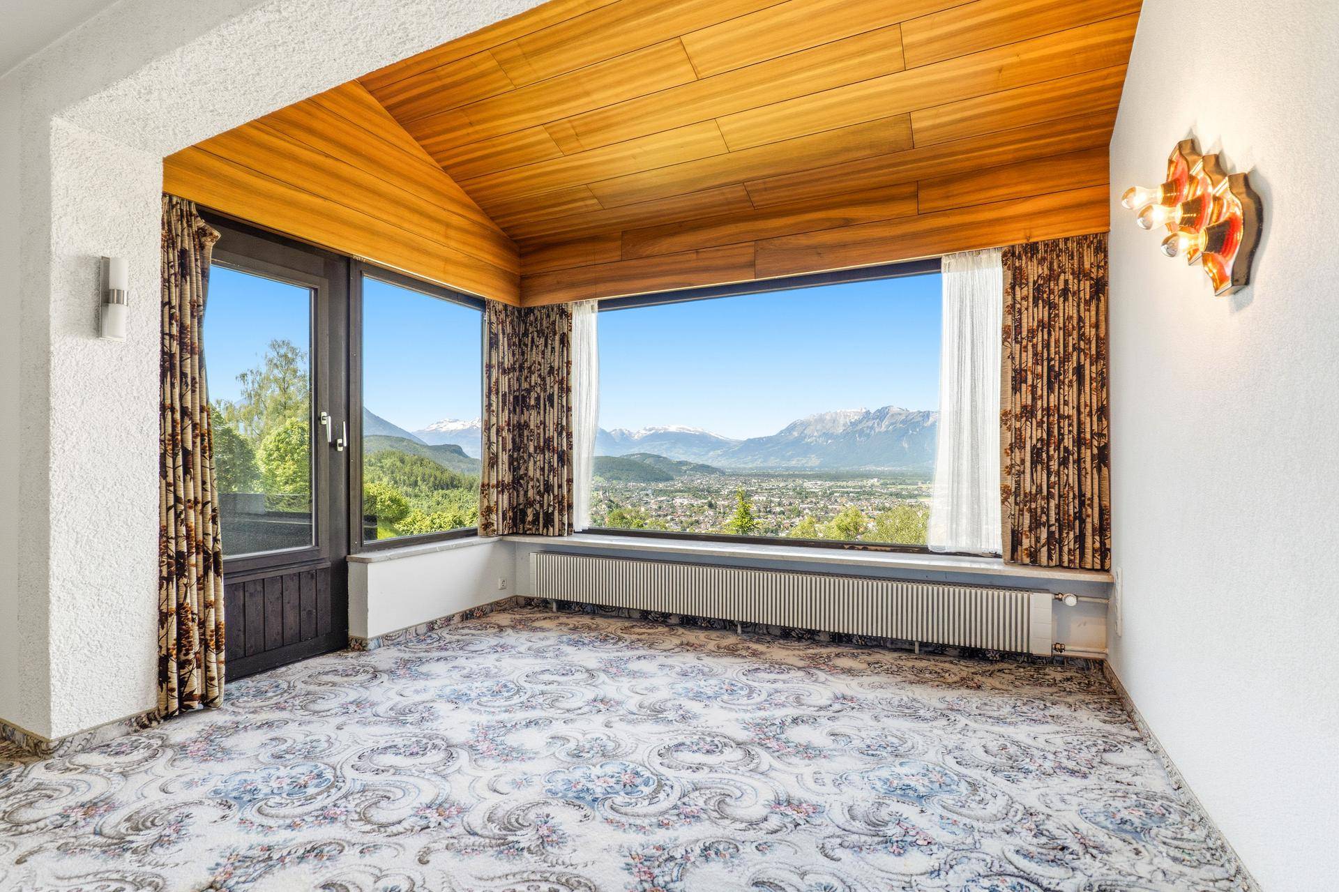 Heller Raum mit großen Fenstern, die einen weiten Blick auf die Berge und die Stadt bieten.