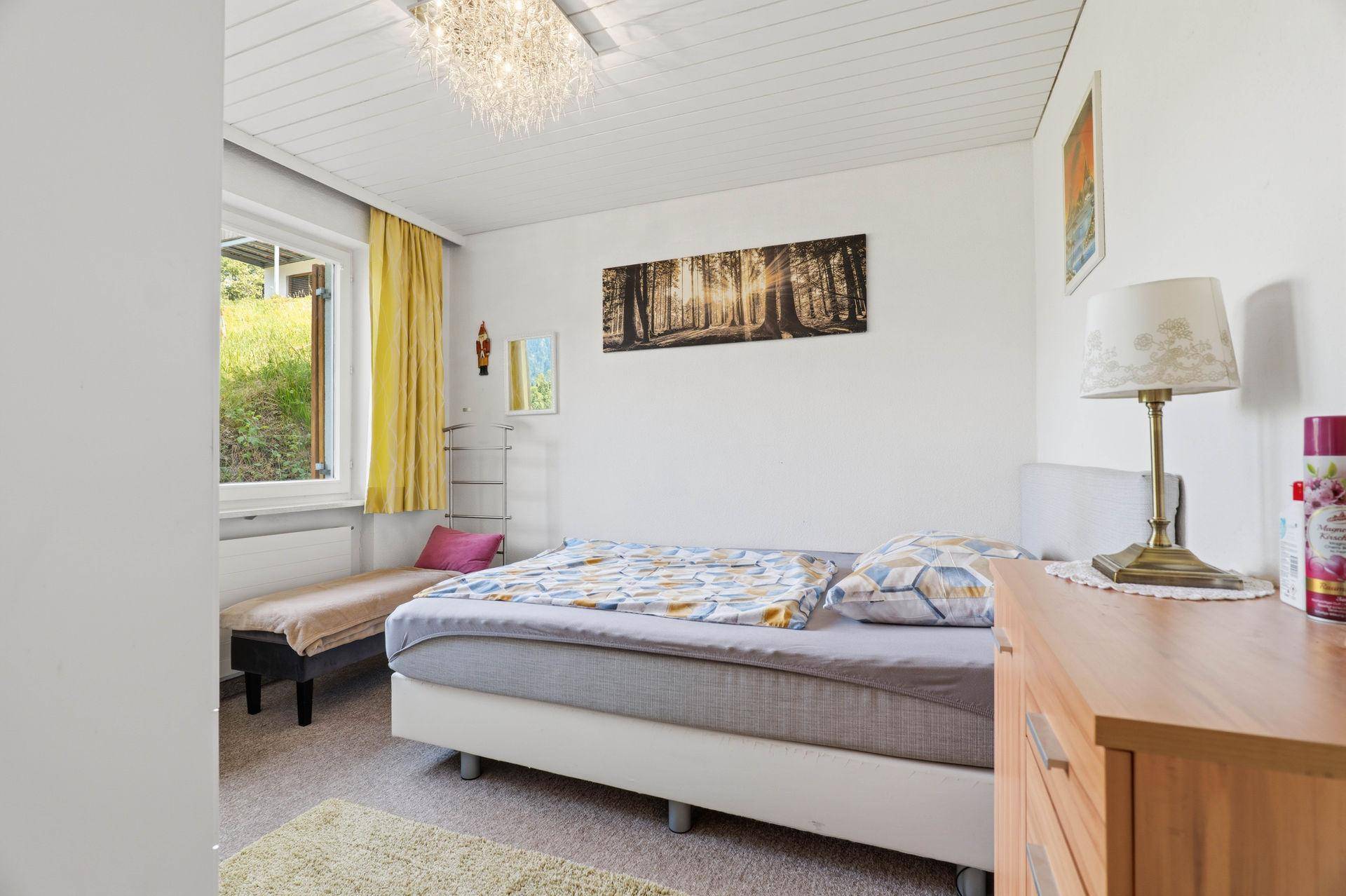 Helles Schlafzimmer mit Teppichboden, Einzelbett und Fenster.