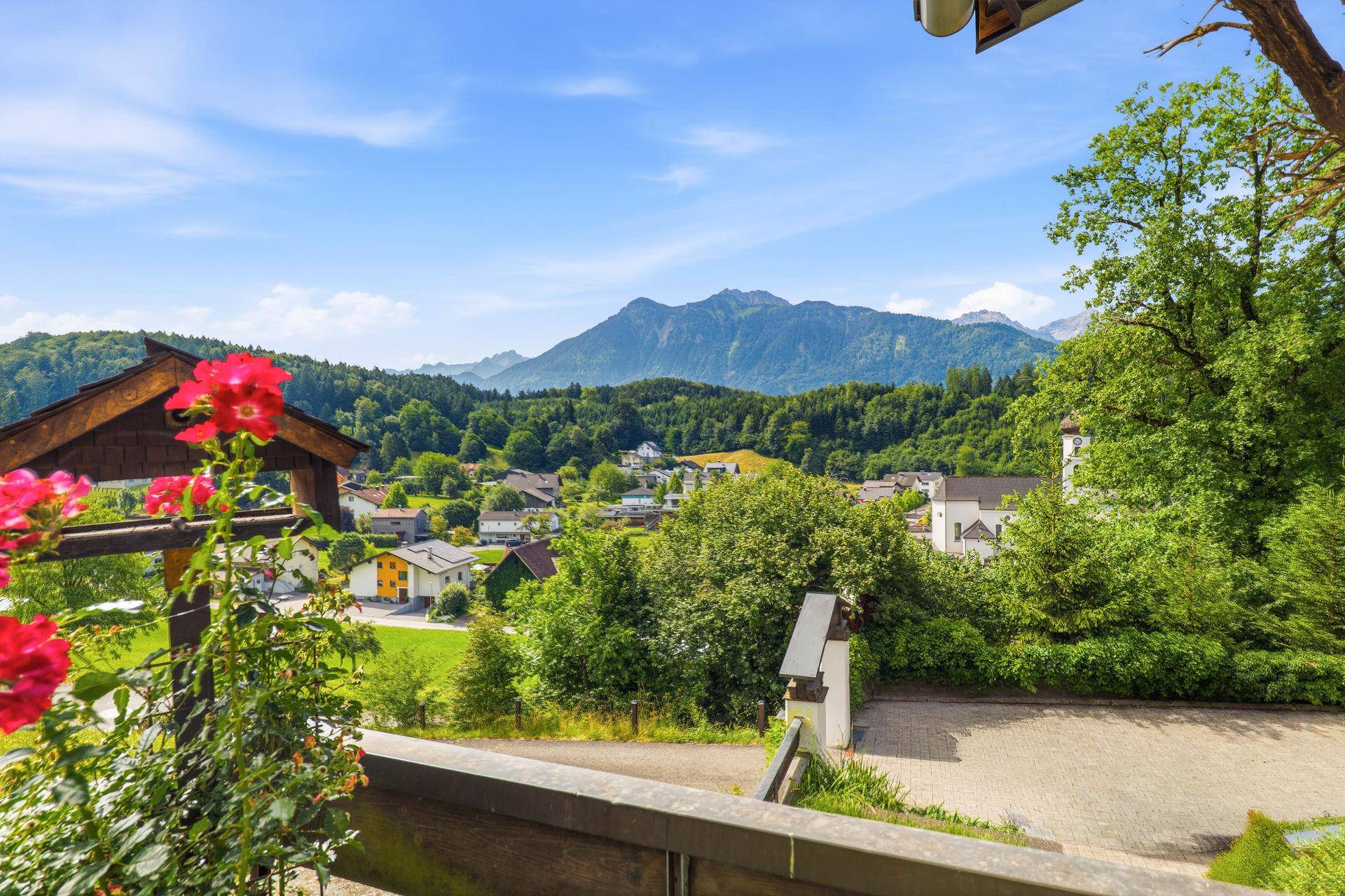 Malerischer Ausblick auf ein Dorf mit Bergen und grünen Hügeln.