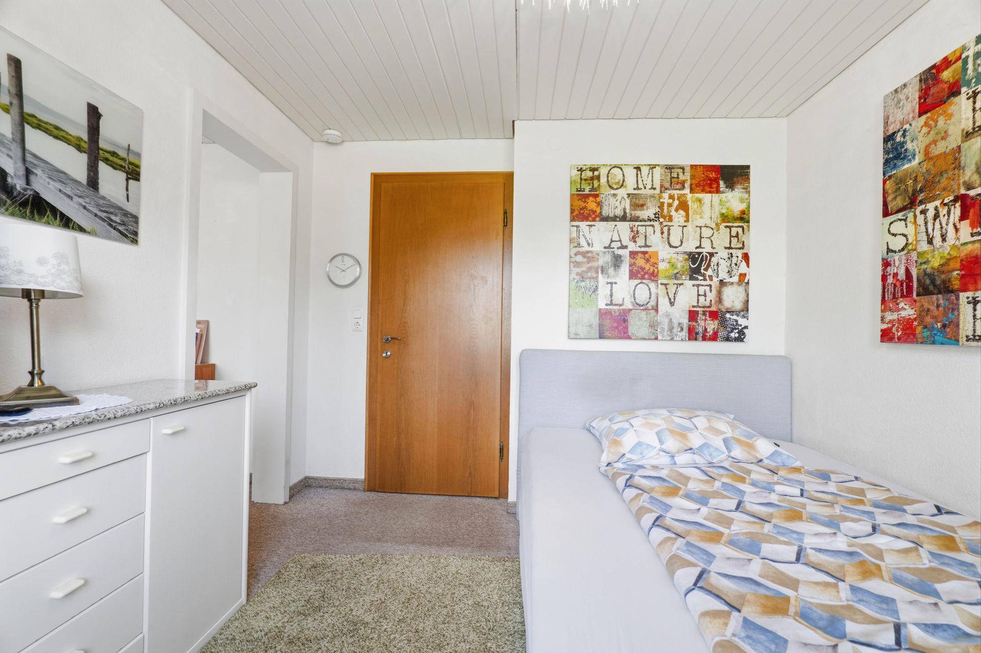 Schlafzimmer mit Teppichboden, Holzdecke und farbenfroher Dekoration.
