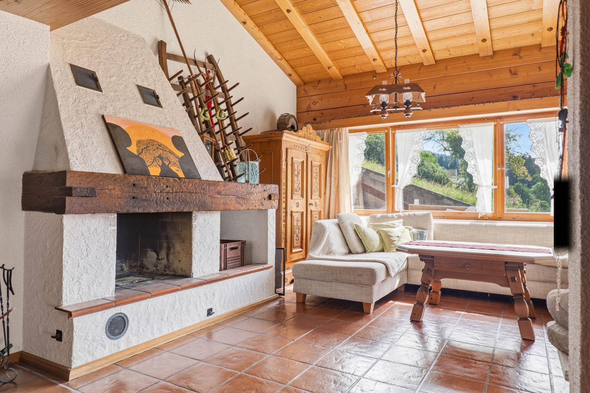 Rustikales Wohnzimmer mit großem Kamin, Holzbalkendecke und traditionellen Möbeln.