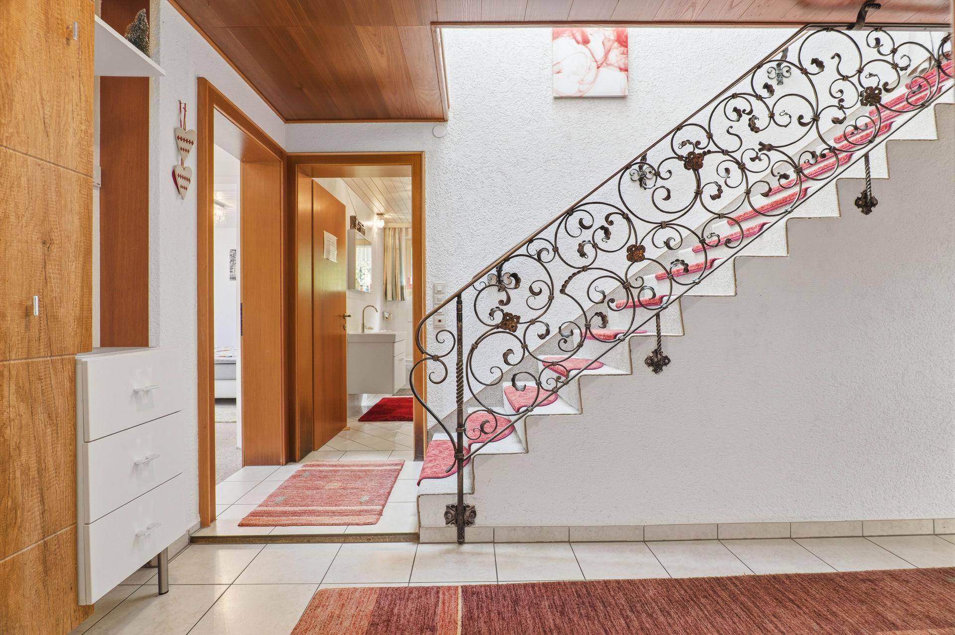 Eingangsbereich mit schmiedeeiserner Treppe und Holzdecke.