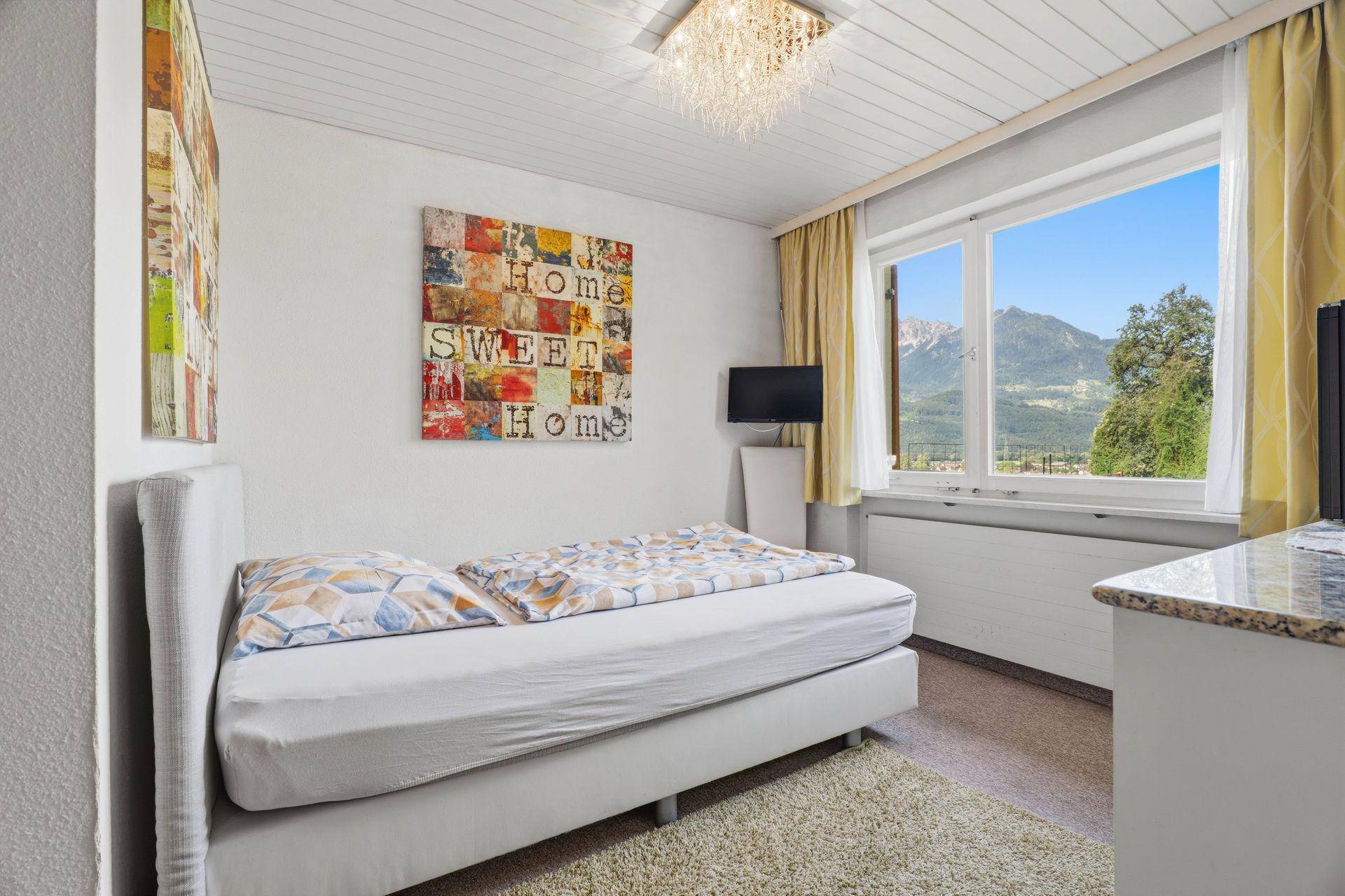 Gemütliches Schlafzimmer mit Einzelbett, Teppichboden und Bergblick.