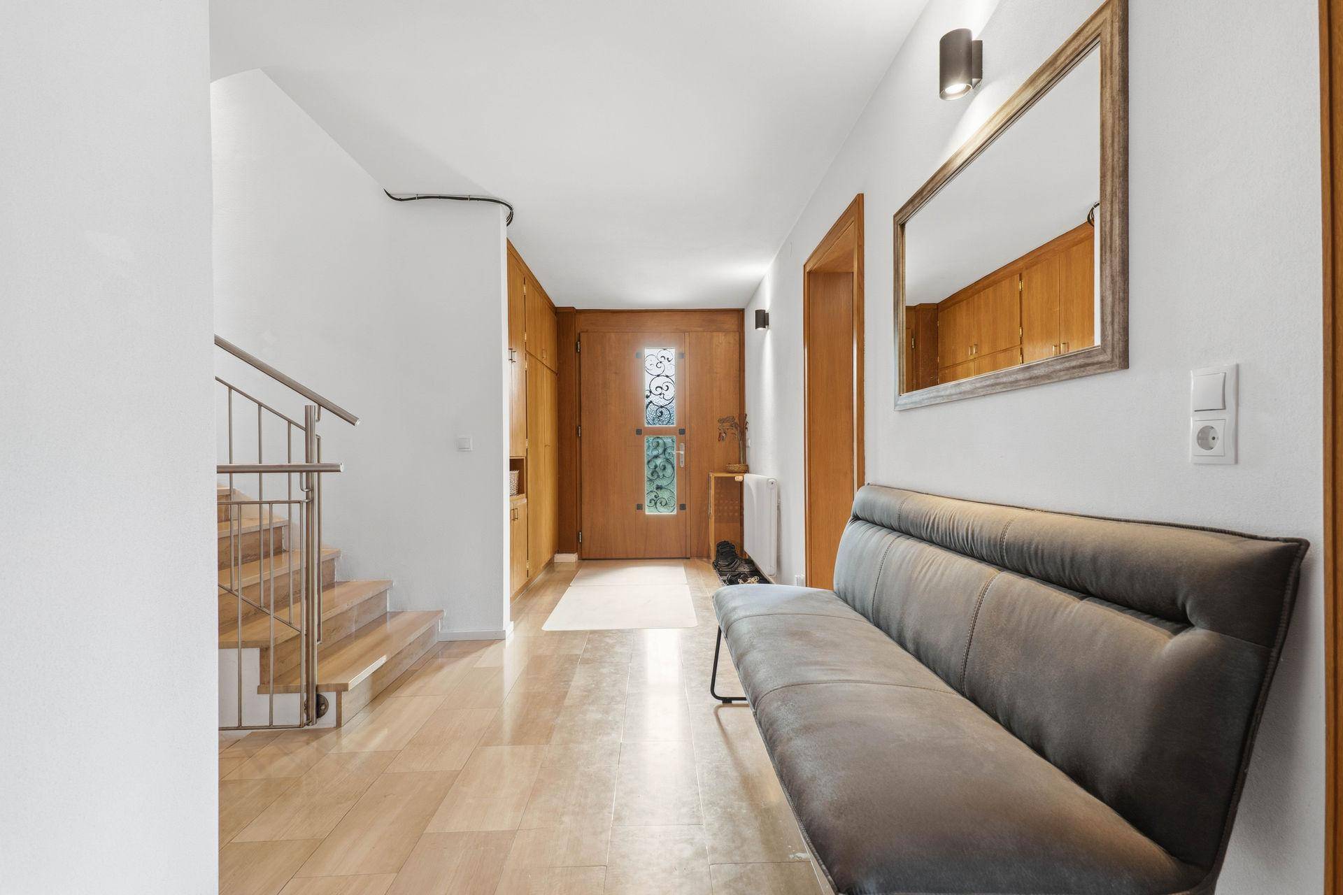 Geräumiger Eingangsbereich mit heller Fliese, moderner Sitzbank und Holztür mit Glaseinsatz.