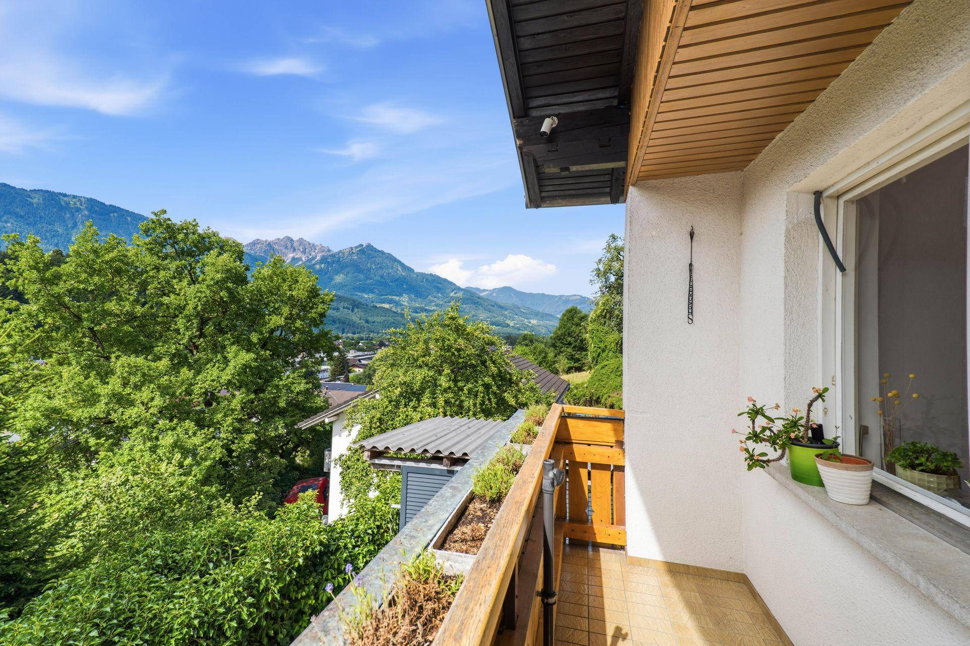 Kleiner Balkon mit Holzboden und atemberaubendem Blick auf die umliegenden Berge und das Tal.