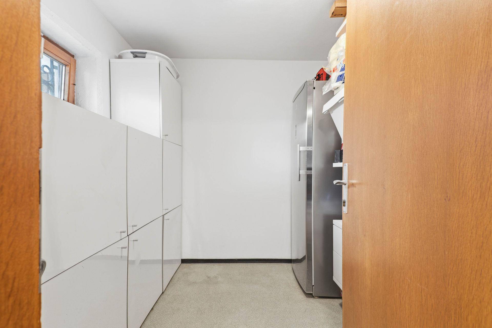 Abstellraum mit Regalen, Schränken und einem großen Kühlschrank.