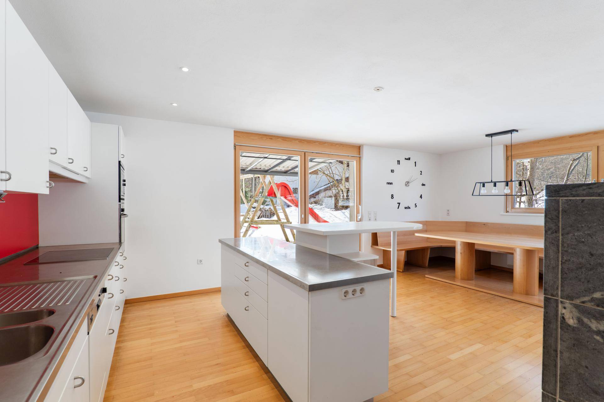 Küche mit Essbereich und Zugang zu einer Terrasse mit Kinderspielplatz im verschneiten Garten.