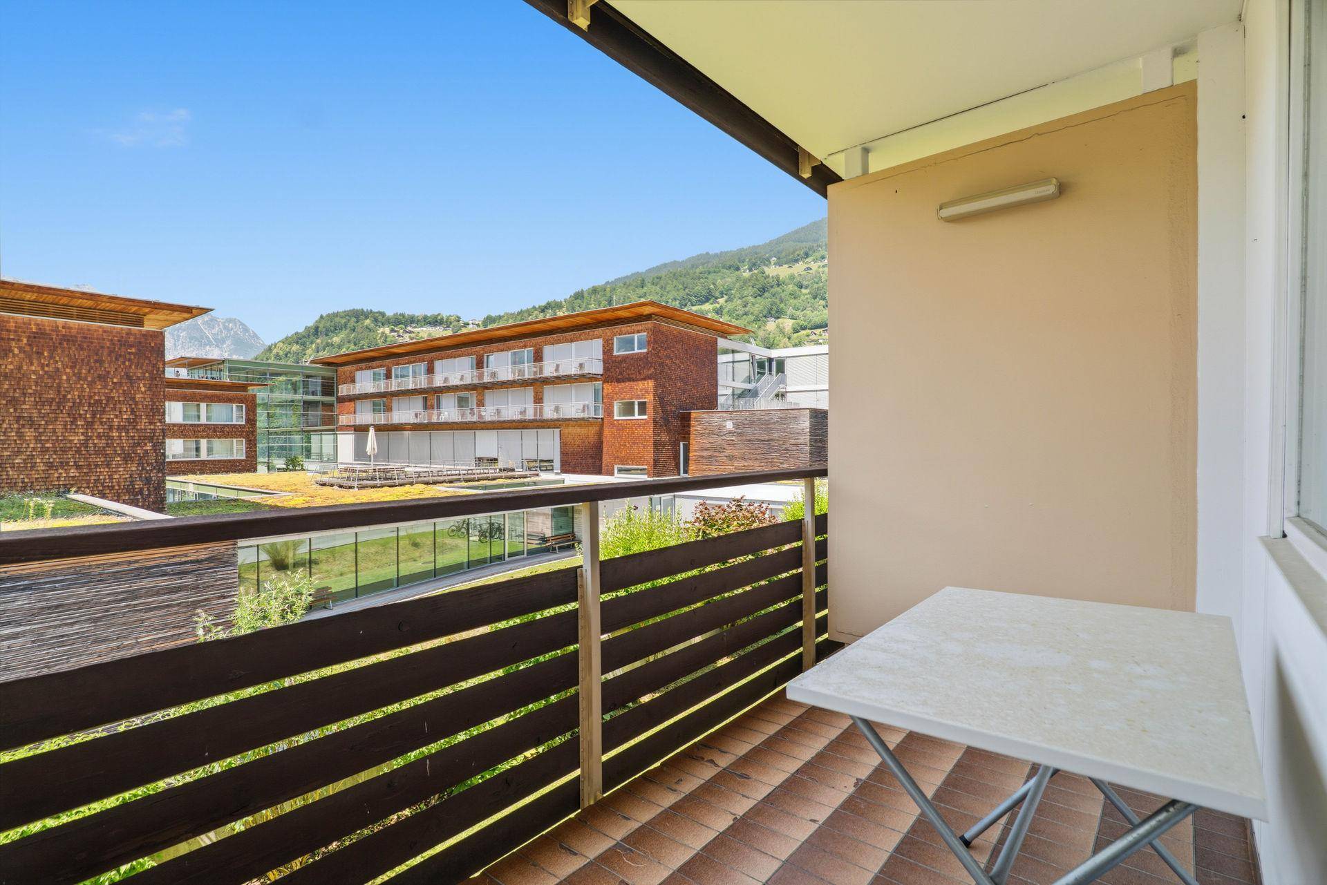 Kleiner Balkon mit Tisch und Stuhl, bietet einen schönen Blick auf die Umgebung und Berge.