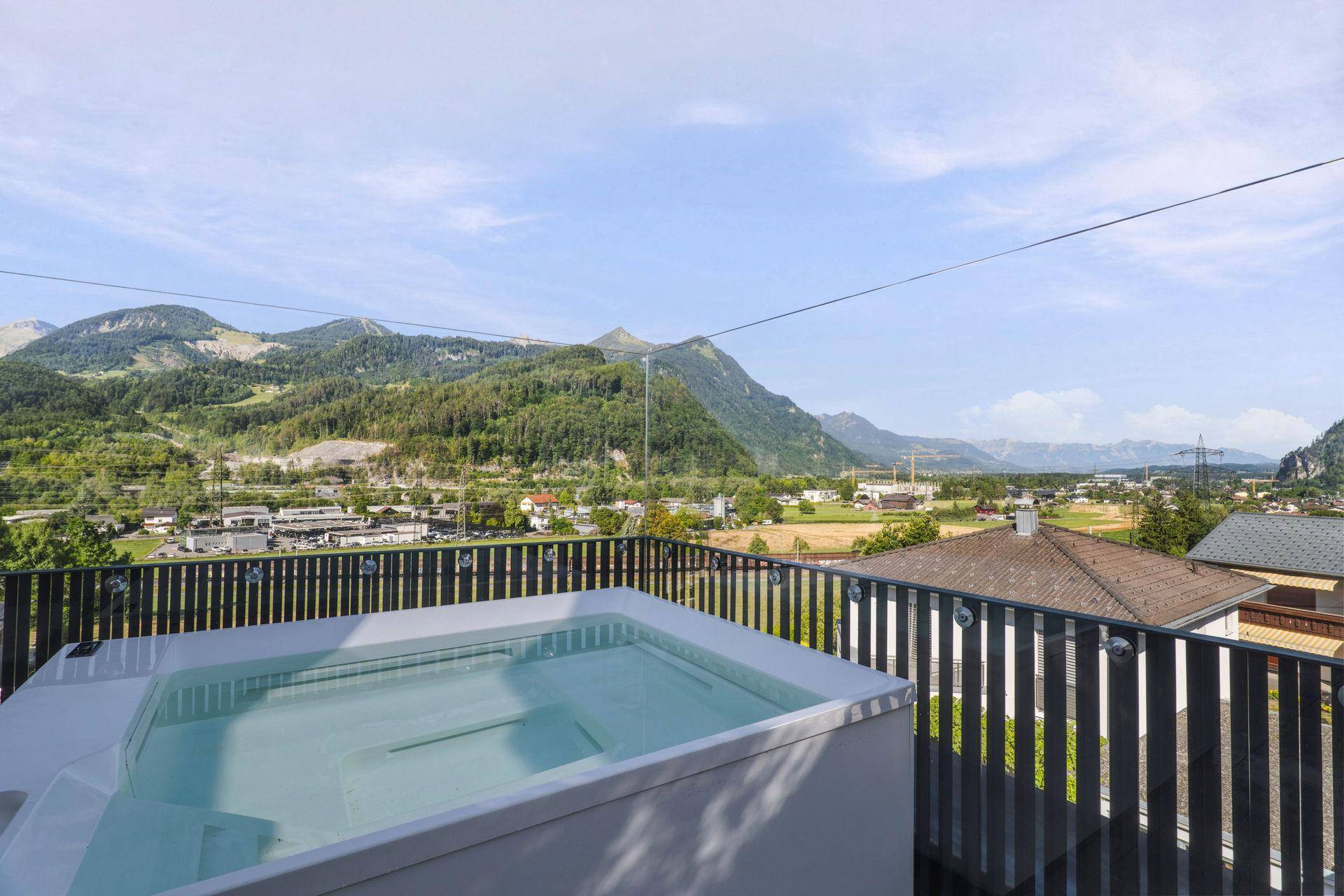 Moderner Whirlpool auf der Terrasse mit Panoramablick auf die grüne Berglandschaft.