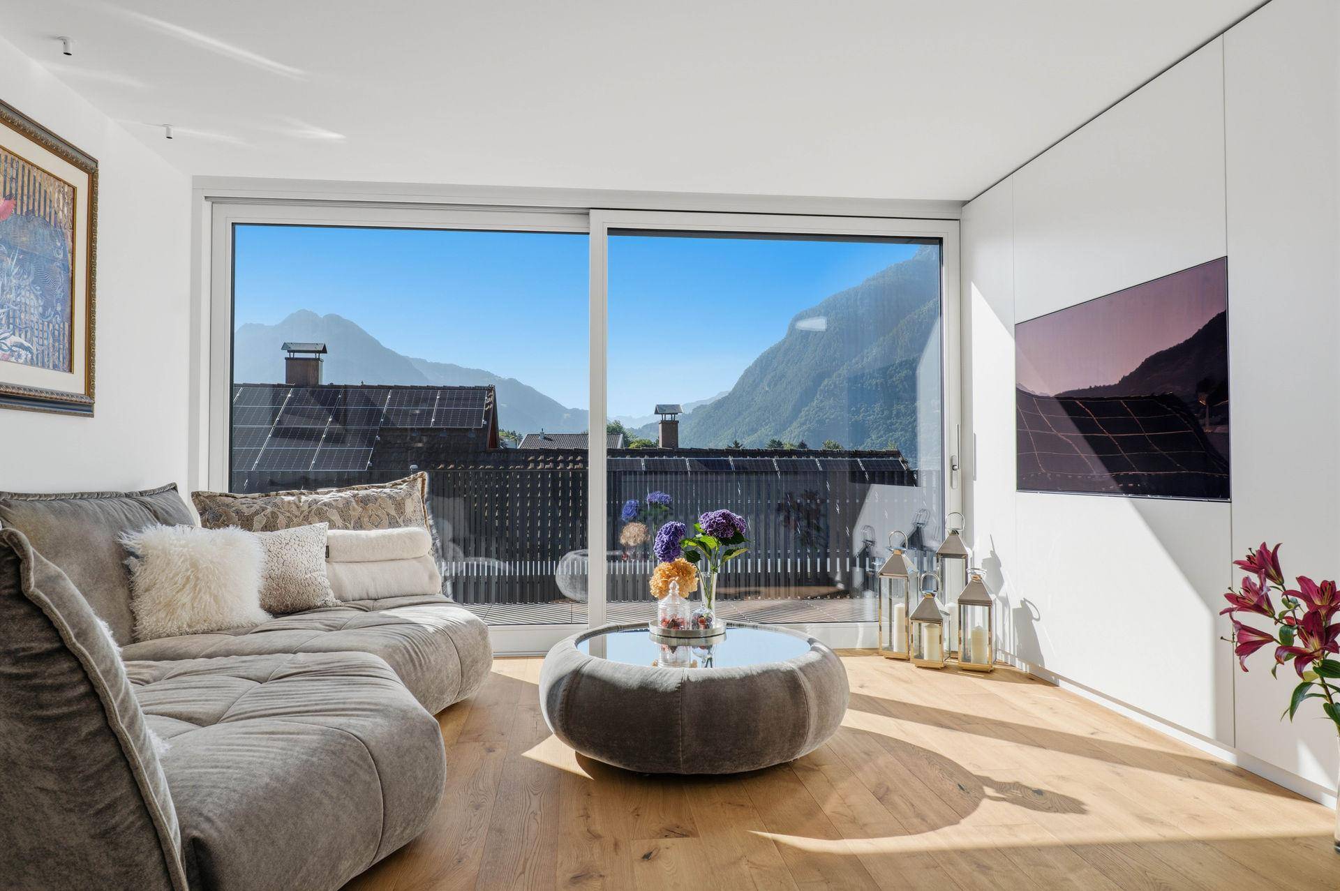 Gemütliches Wohnzimmer mit großem Sofa, Holzboden und weitem Blick auf die Berge.