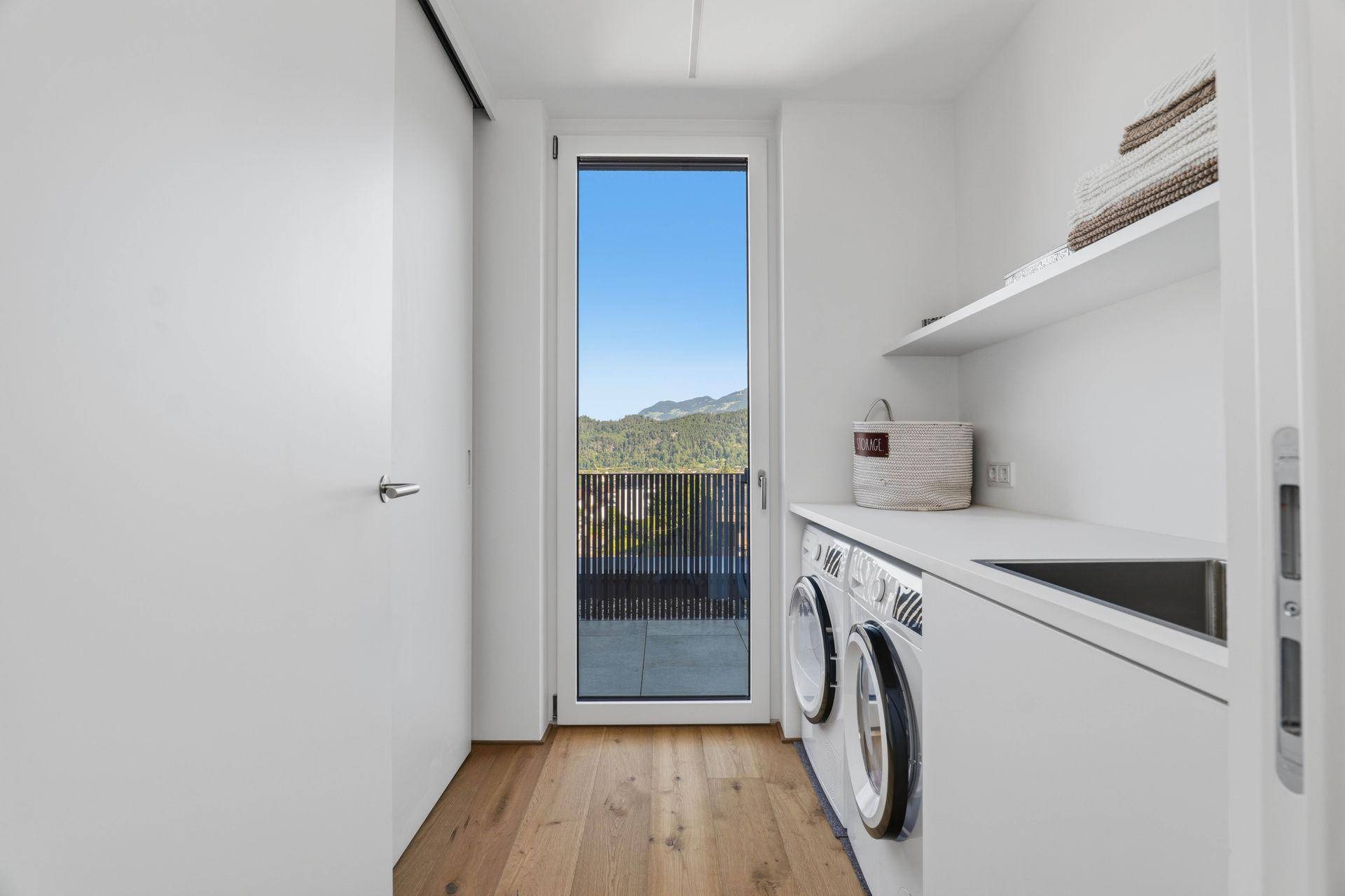 Praktischer Hauswirtschaftsraum mit Waschmaschine, Trockner und Zugang zur Terrasse.
