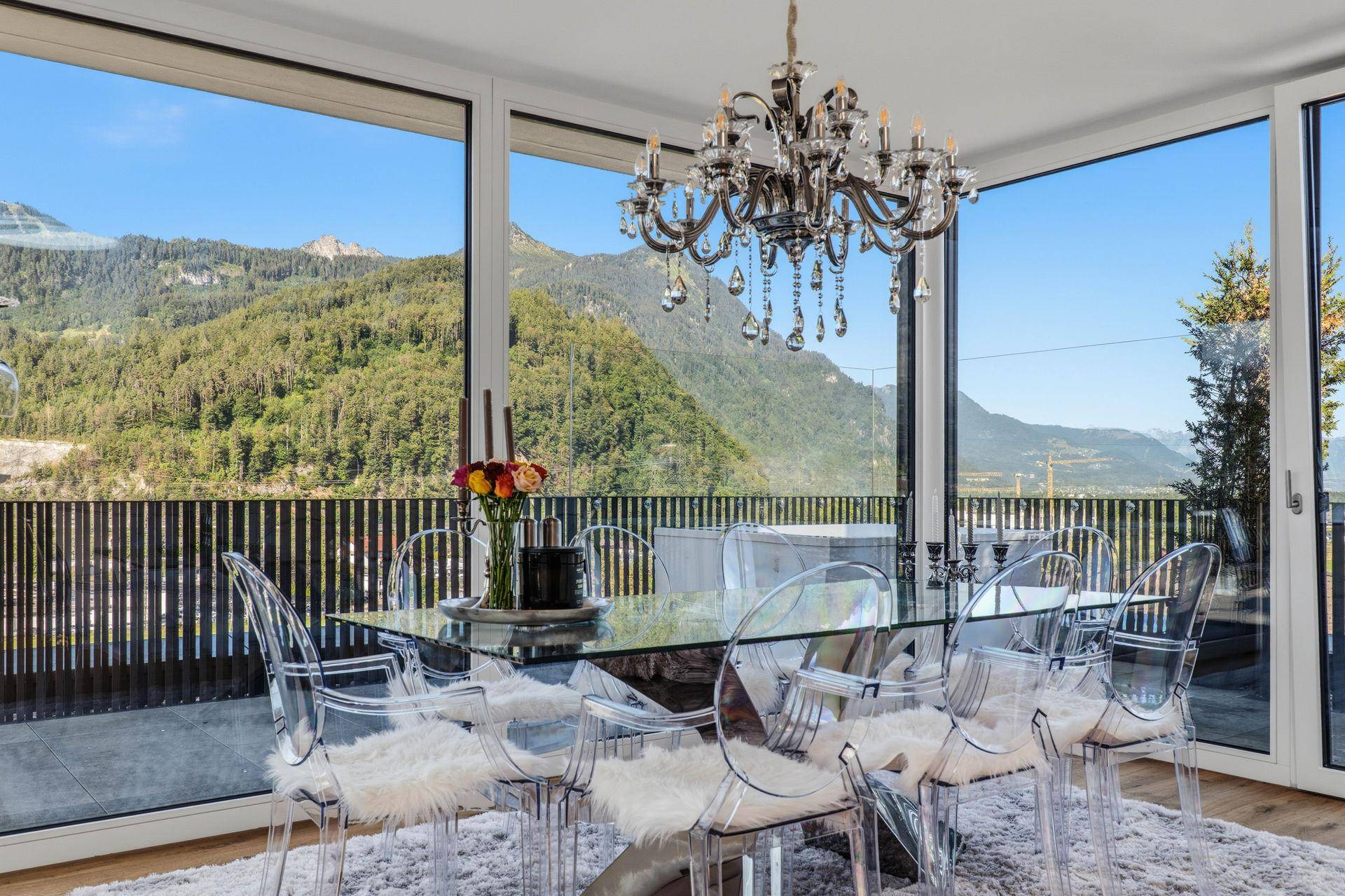 Eleganter Essbereich mit Glasstisch, modernen Stühlen und Panoramablick auf die Berge.
