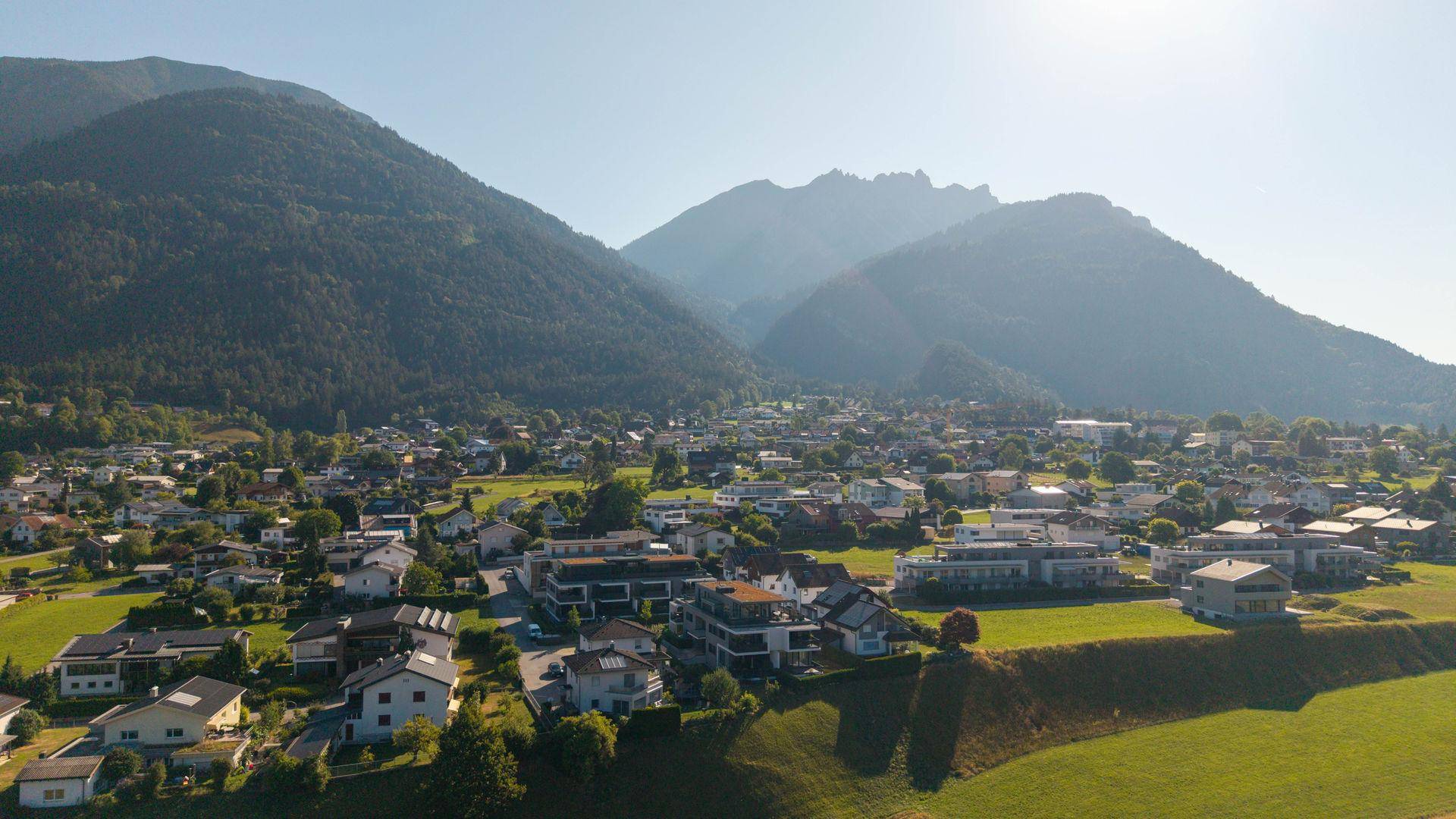 Malerische Ansicht der Wohngegend mit sanften Hügeln und imposanten Bergen am Horizont.