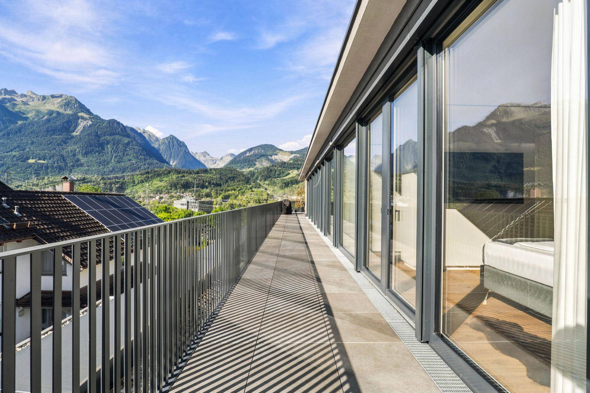 Lange Terrasse mit Fliesenboden und weitem Blick auf die Berge und die Umgebung.